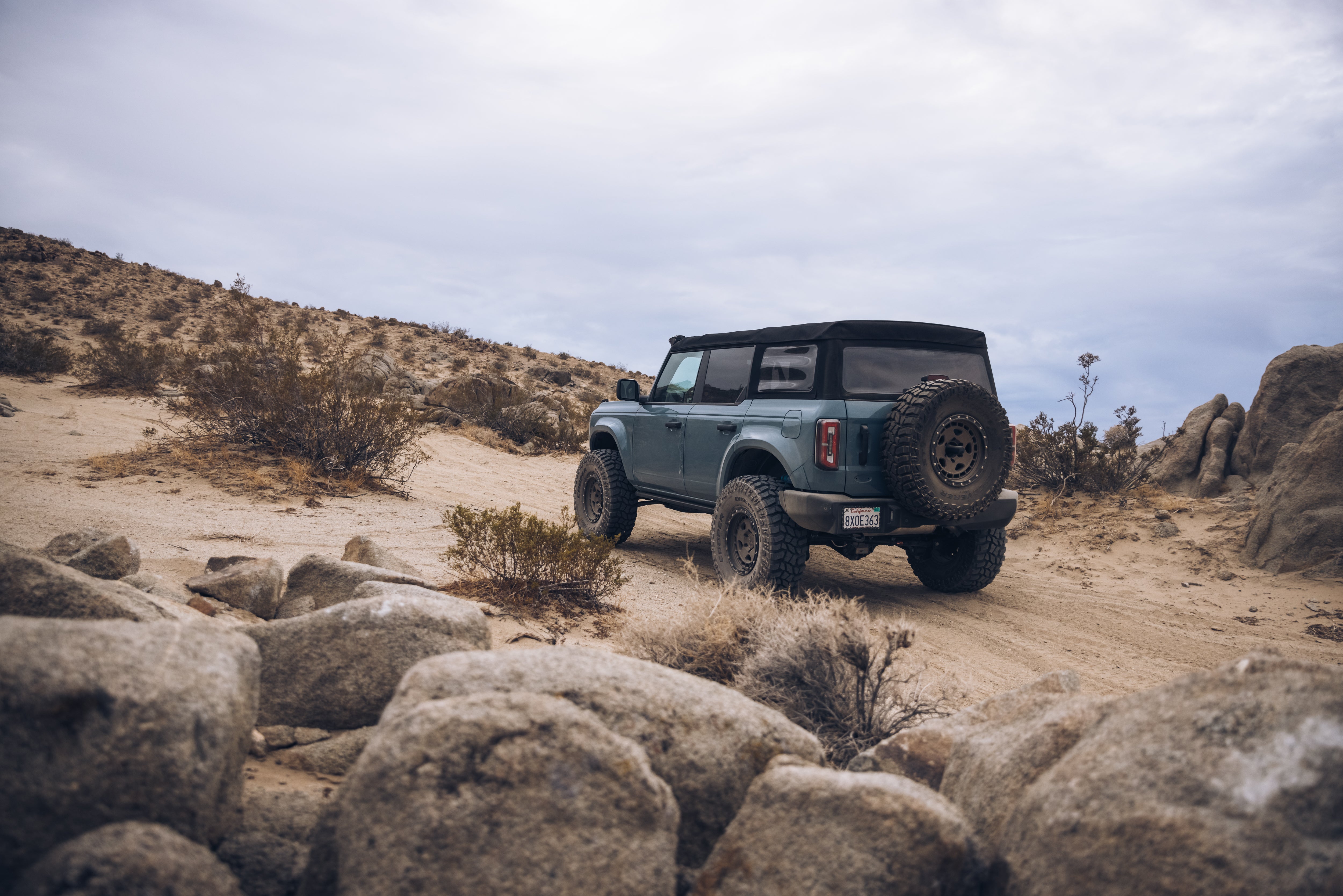 ADV Fiberglass 2021 Ford vehicle navigating a rugged off-road terrain with rocky landscape and desert vegetation.