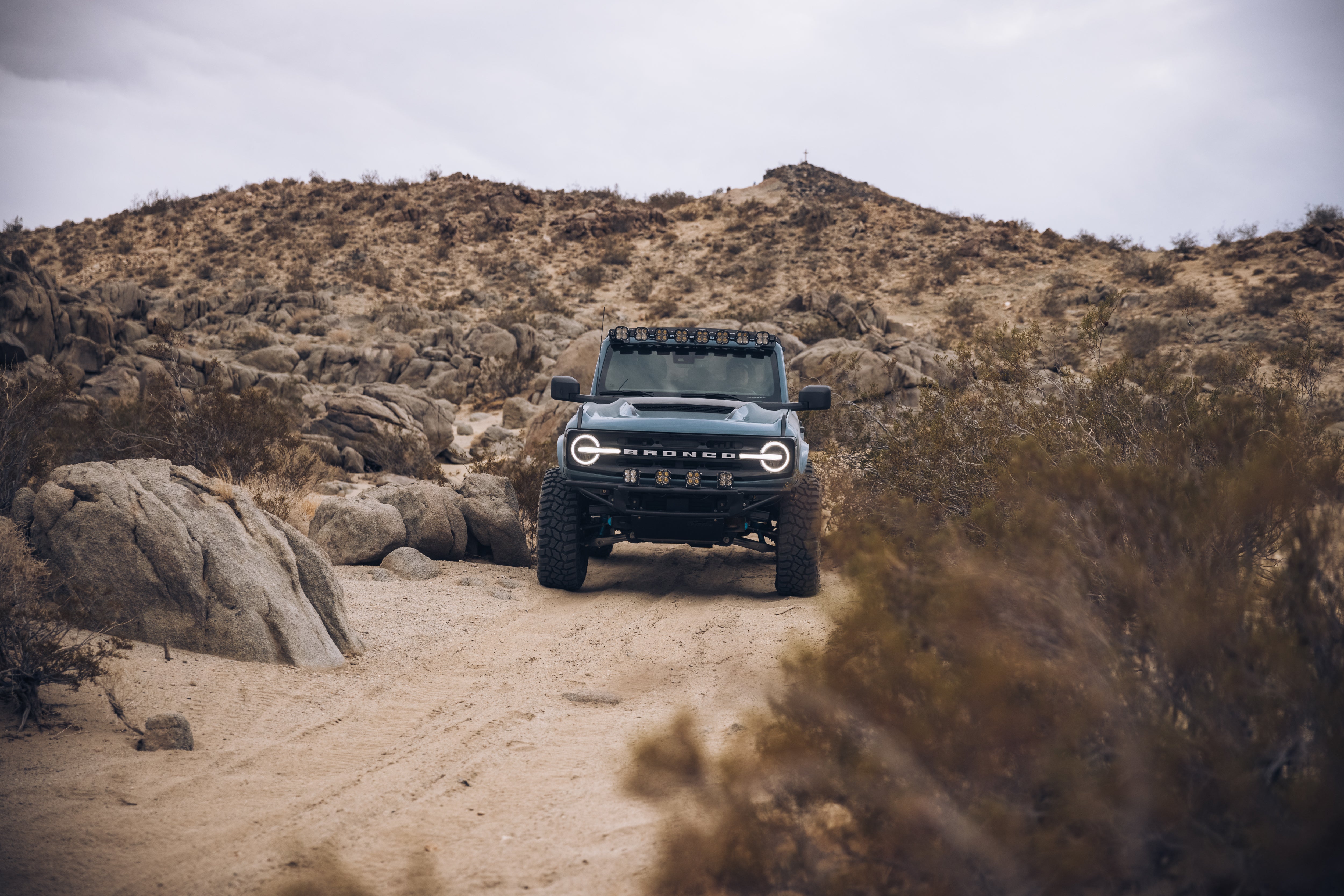 ADV Fiberglass 2021 Ford Bronco navigating rocky terrain in a desert landscape, showcasing off-road capabilities.