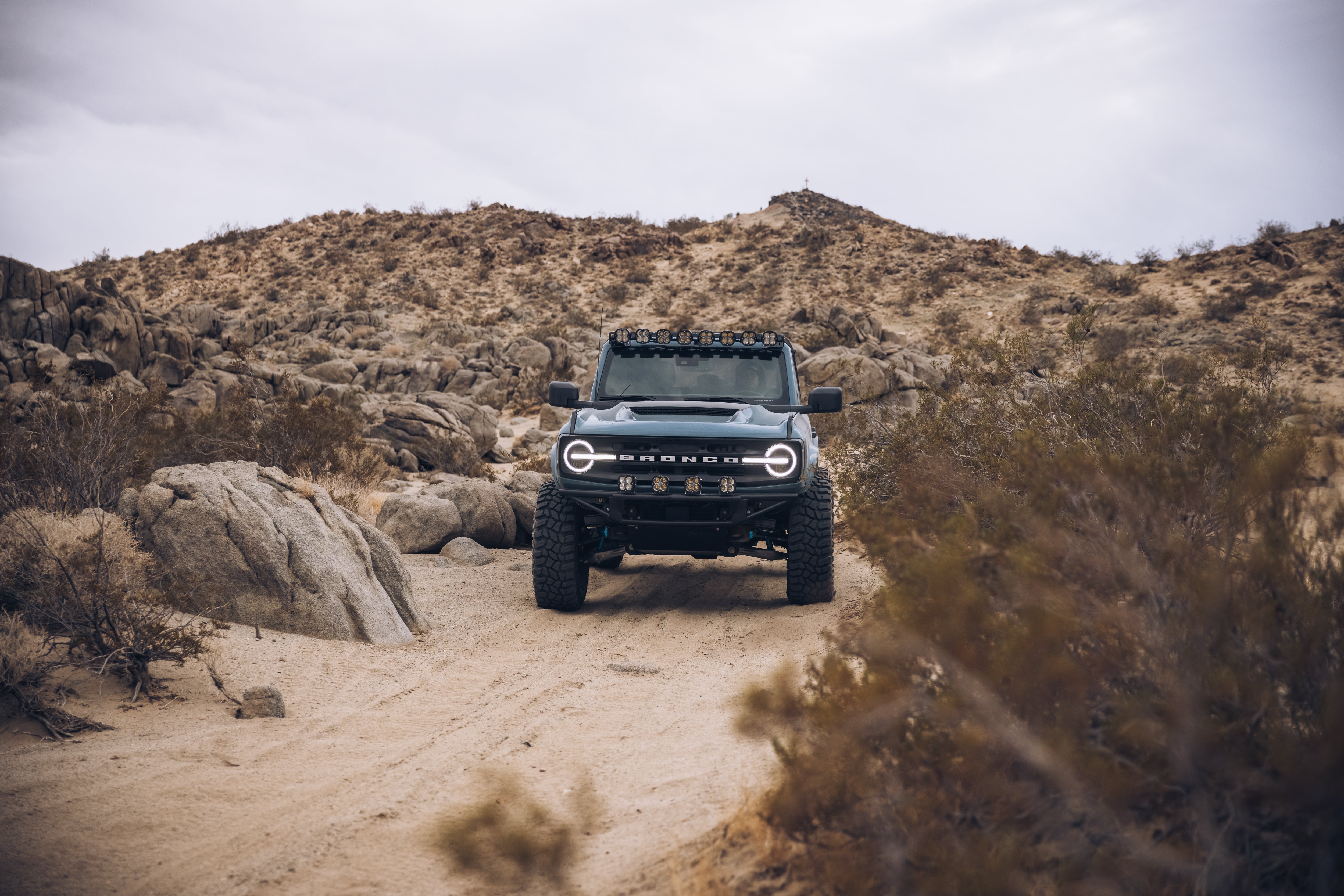 ADV Fiberglass 2021 Ford Bronco on a rugged off-road trail surrounded by rocky terrain and desert vegetation.