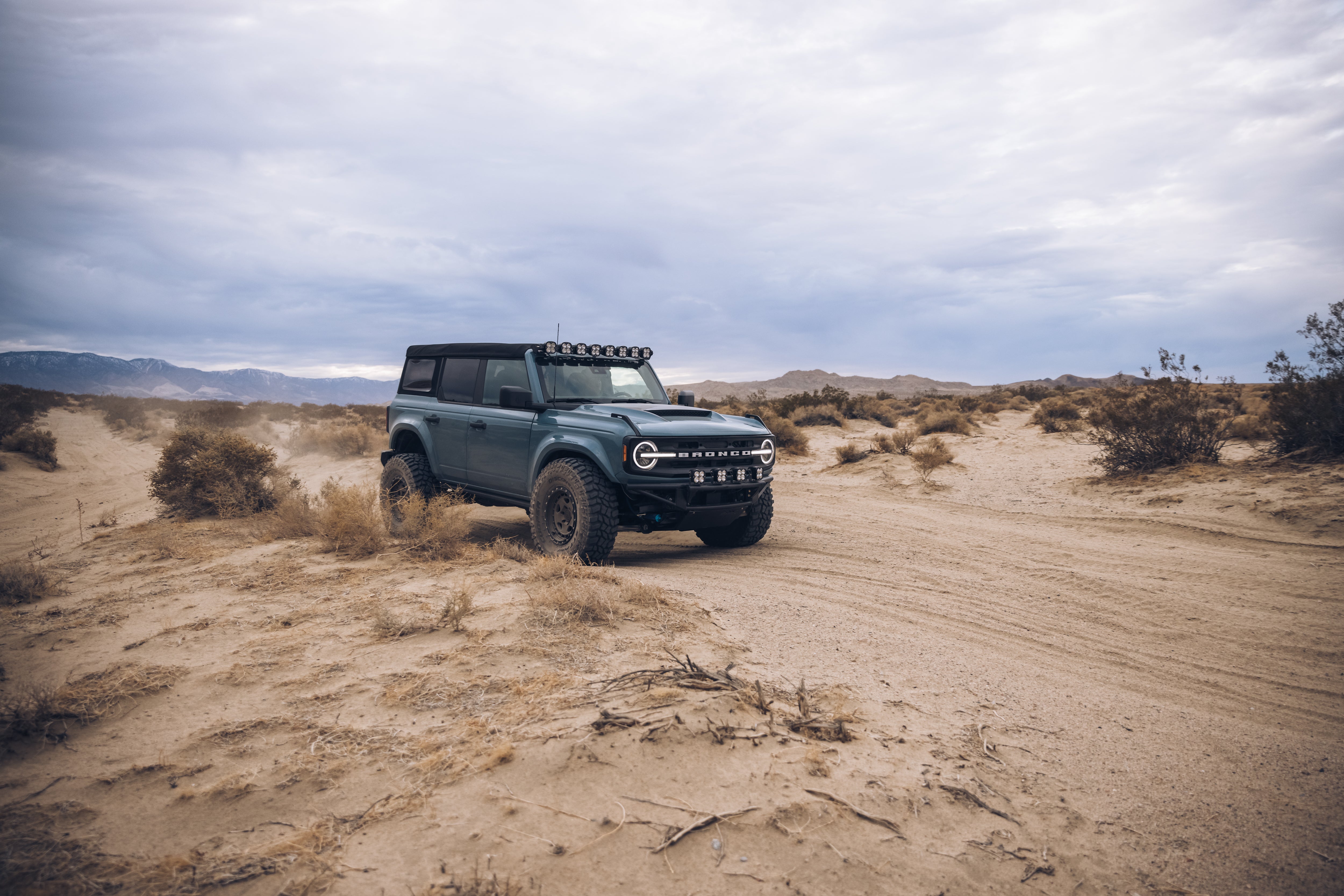 ADV Fiberglass 2021 Ford Bronco off-roading in a desert landscape, showcasing rugged design and performance features.