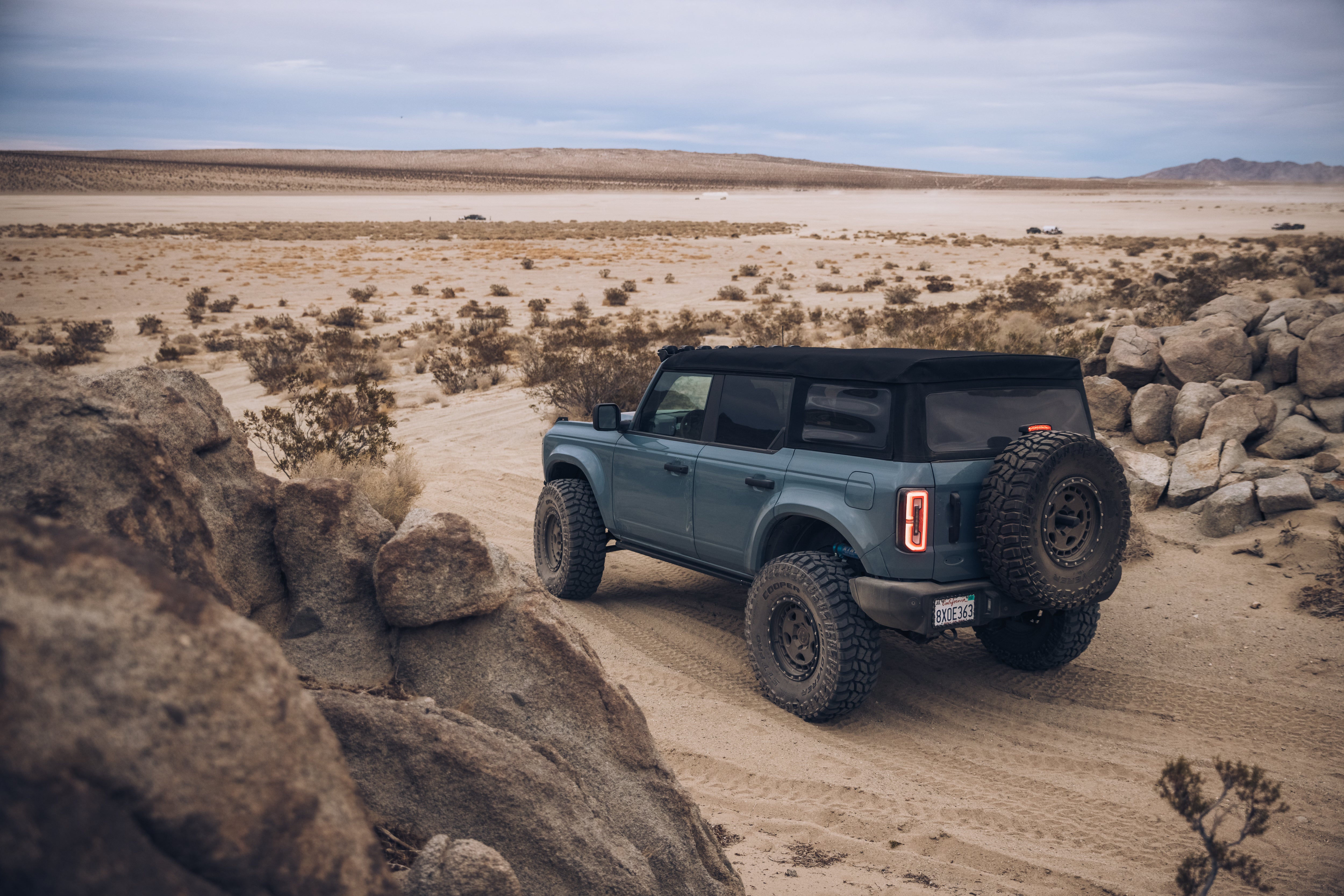 ADV Fiberglass 2021 Ford off-road vehicle navigating a sandy landscape with rocky terrain in the background.