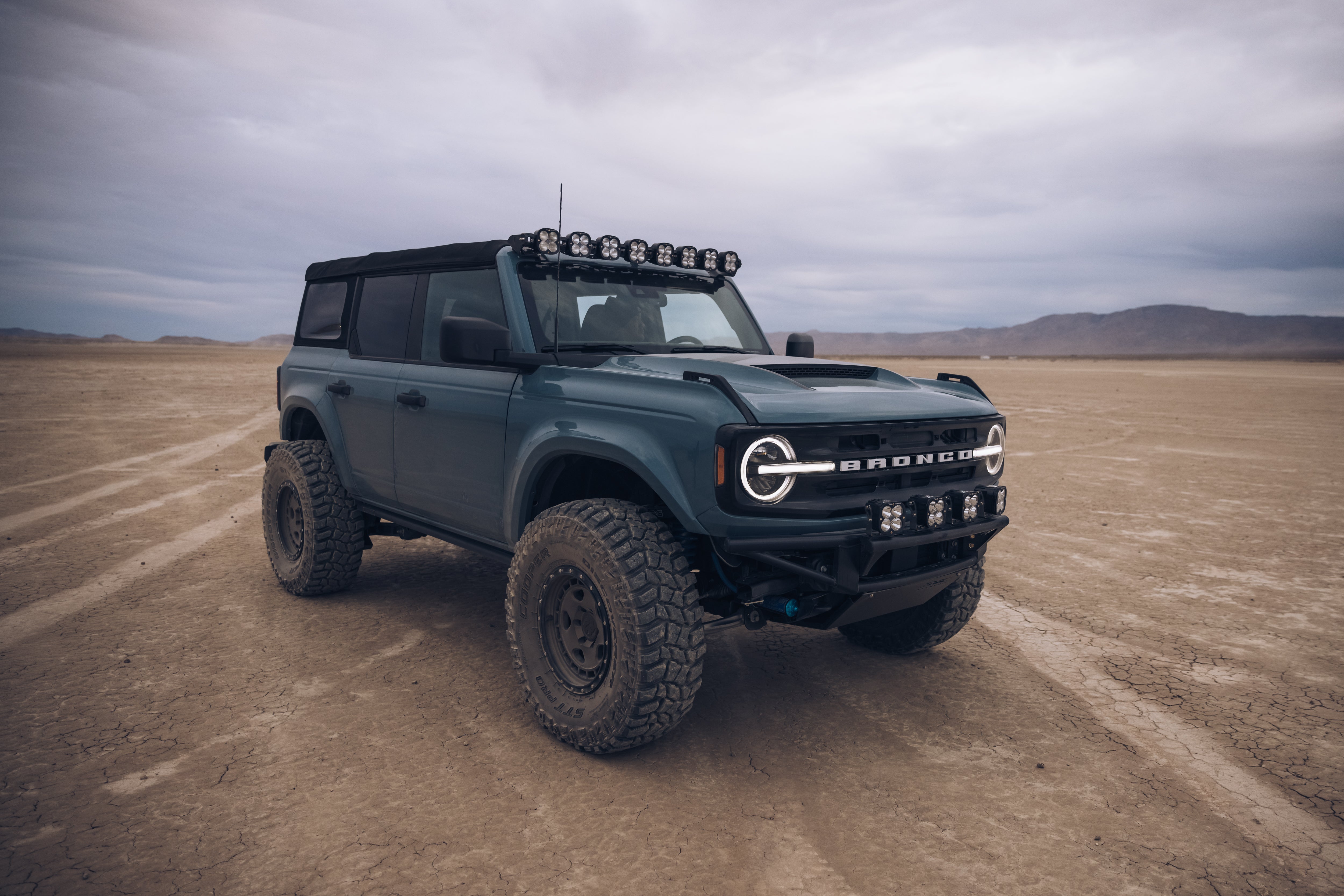 ADV Fiberglass 2021 Ford Bronco with off-road tires and LED light bar, parked on a rugged desert landscape.