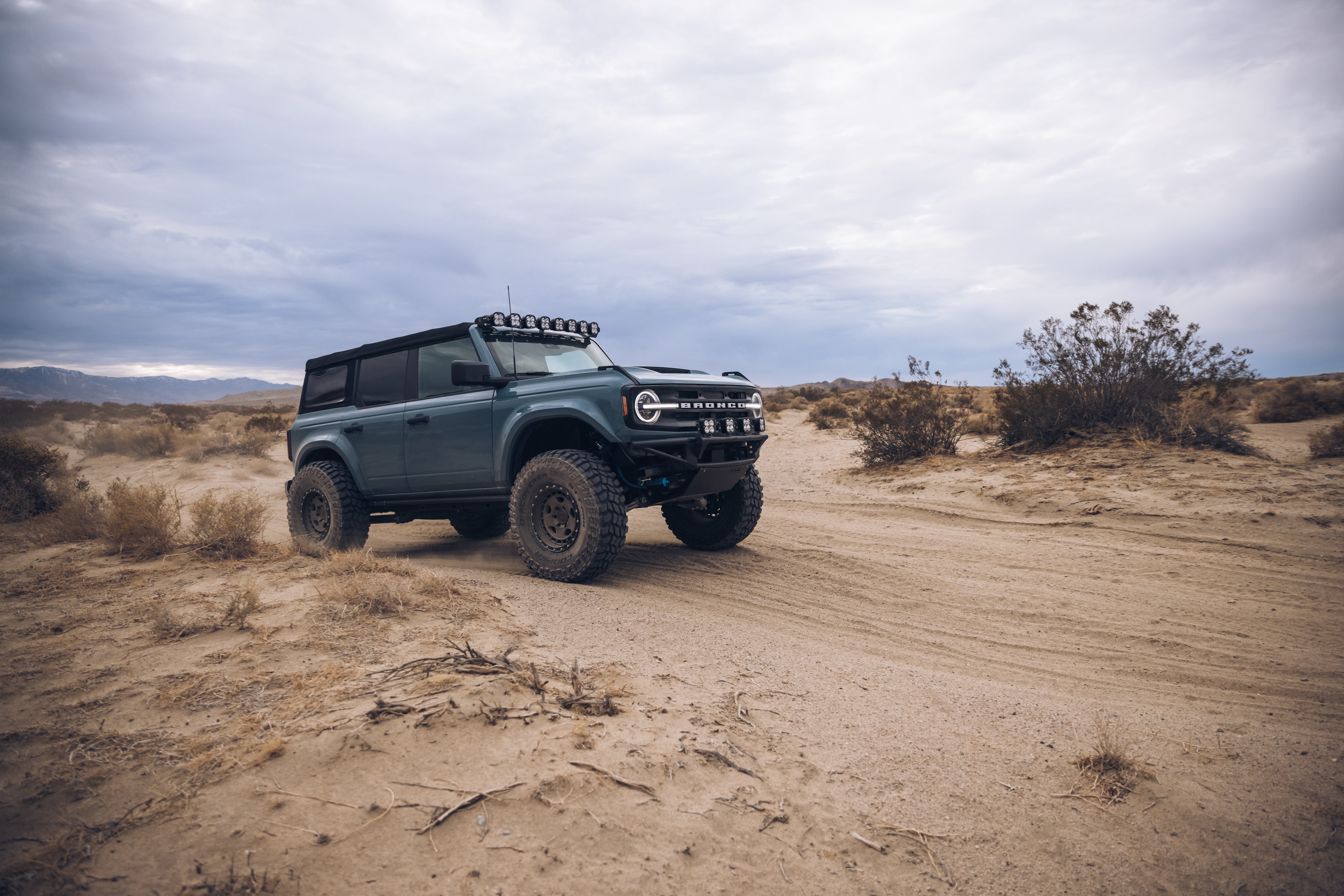 ADV Fiberglass 2021 Ford Bronco equipped for off-roading, showcasing rugged tires and a custom roof rack in a desert landscape.