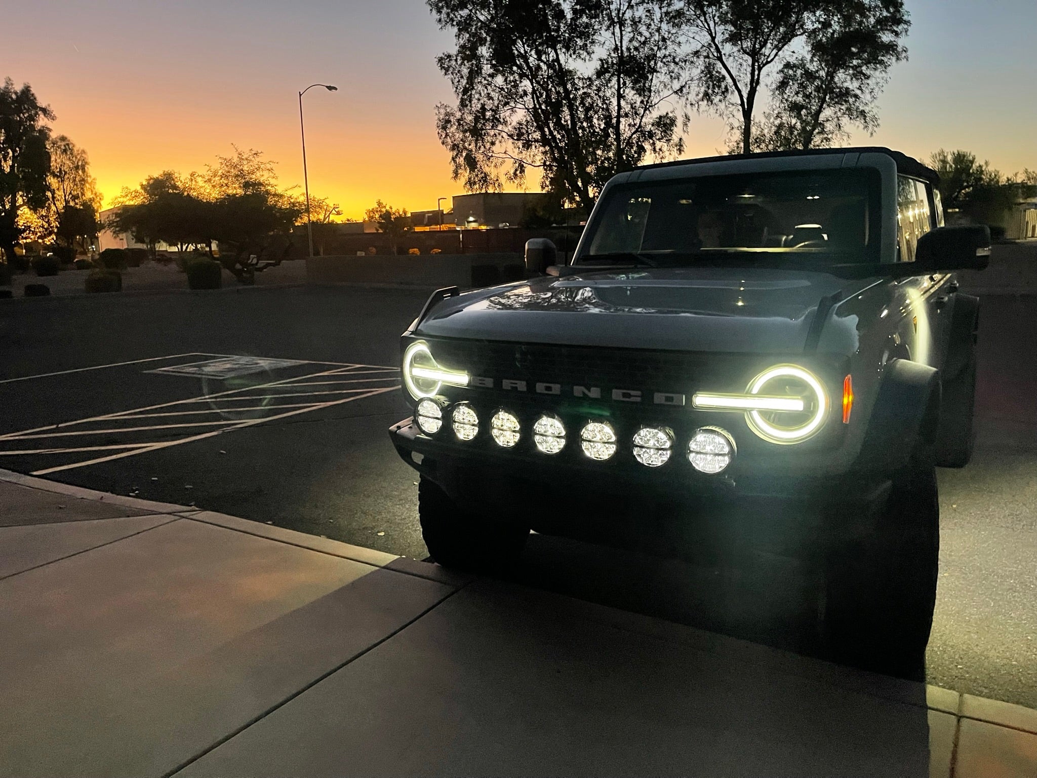 6th Gen Bronco Front Light Mount Kit installed on a Bronco, showcasing multiple lights against a sunset backdrop.