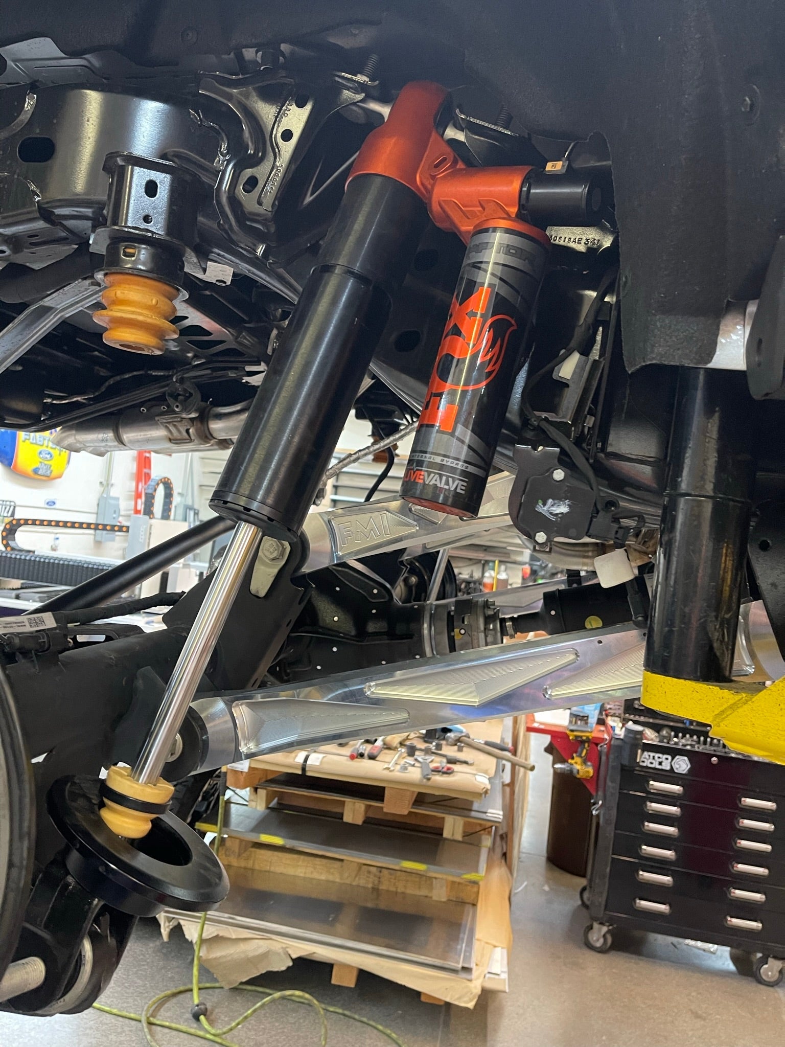 Bronco Raptor billet aluminum rear suspension lower arms installed with shock absorbers in a workshop setting.