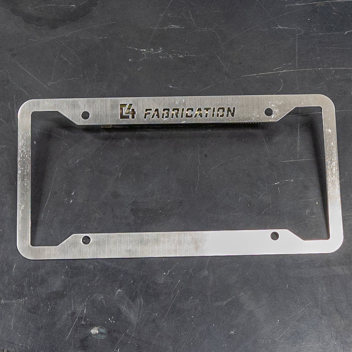 C4 License Plate Frame made of brushed metal with engraved logo, designed for durability and style in offroad vehicles.