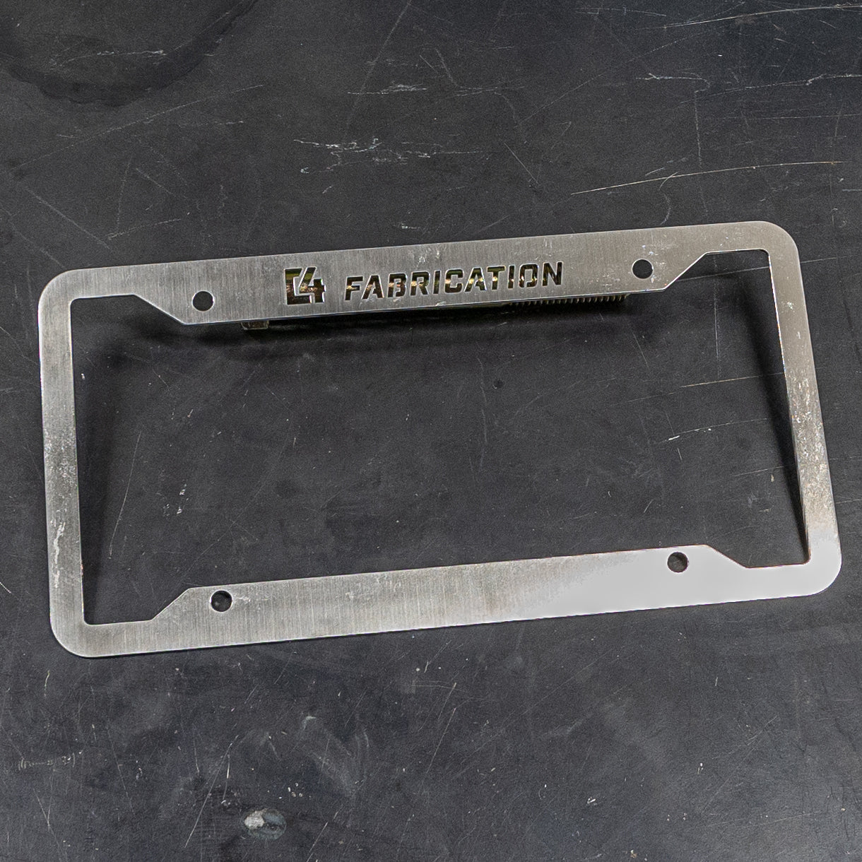 C4 License Plate Frame made of durable metal with a brushed finish and engraved logo, designed for trucks and SUVs.