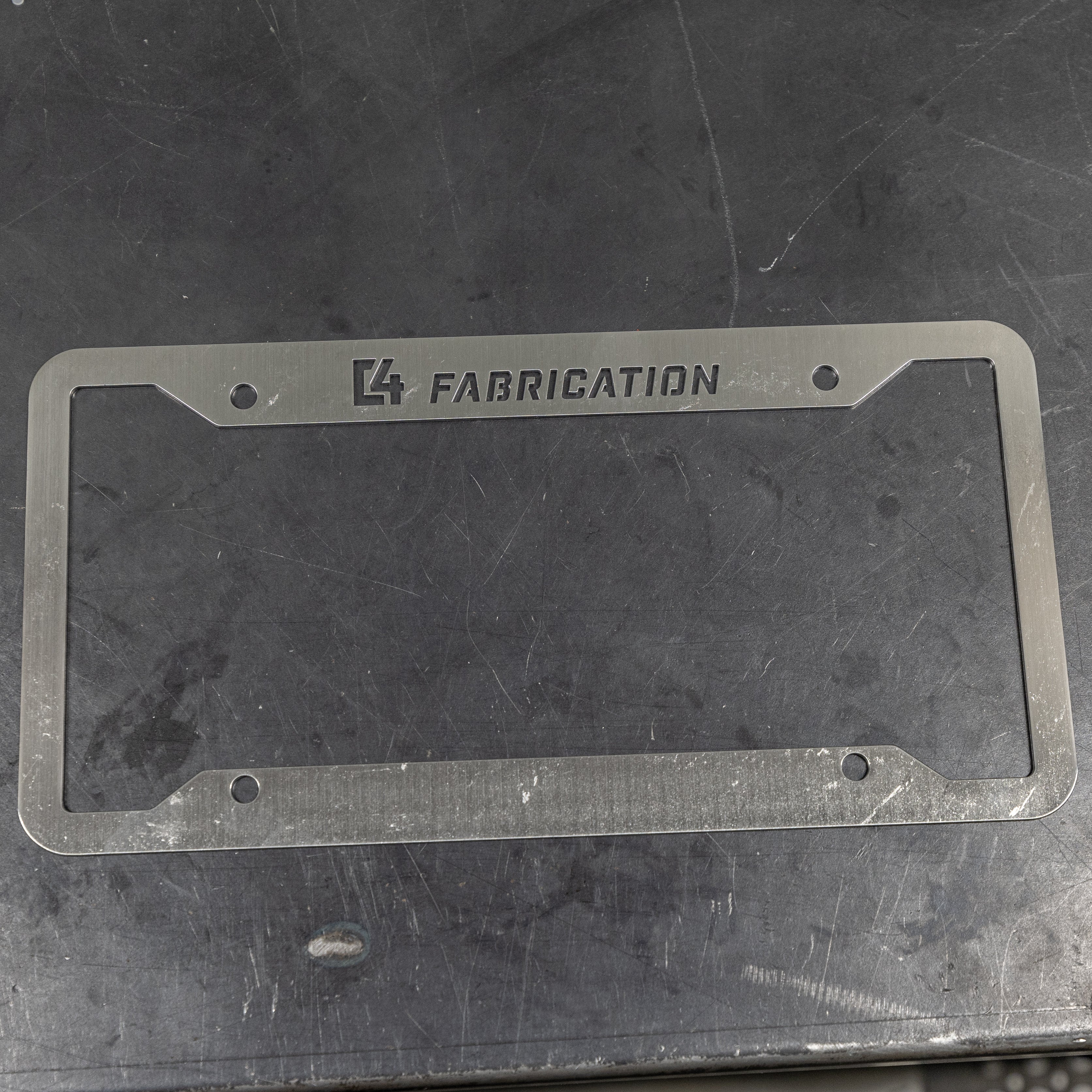 C4 License Plate Frame made of durable metal with engraved branding, designed for offroad vehicles.