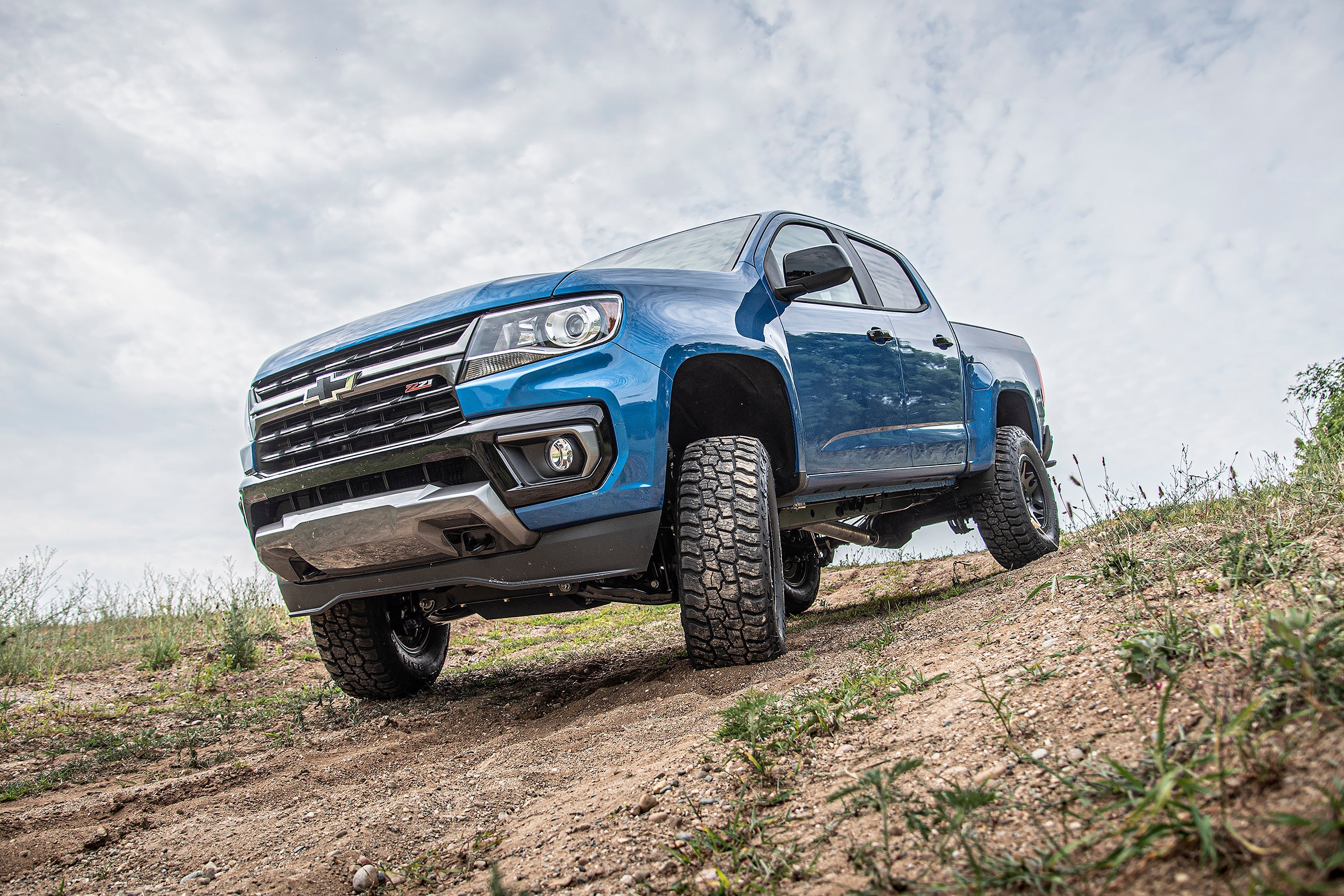 5.5 inch lift kit with FOX 2.5 coil-over installed on a blue Chevy Colorado on rugged terrain, showcasing offroad capability.