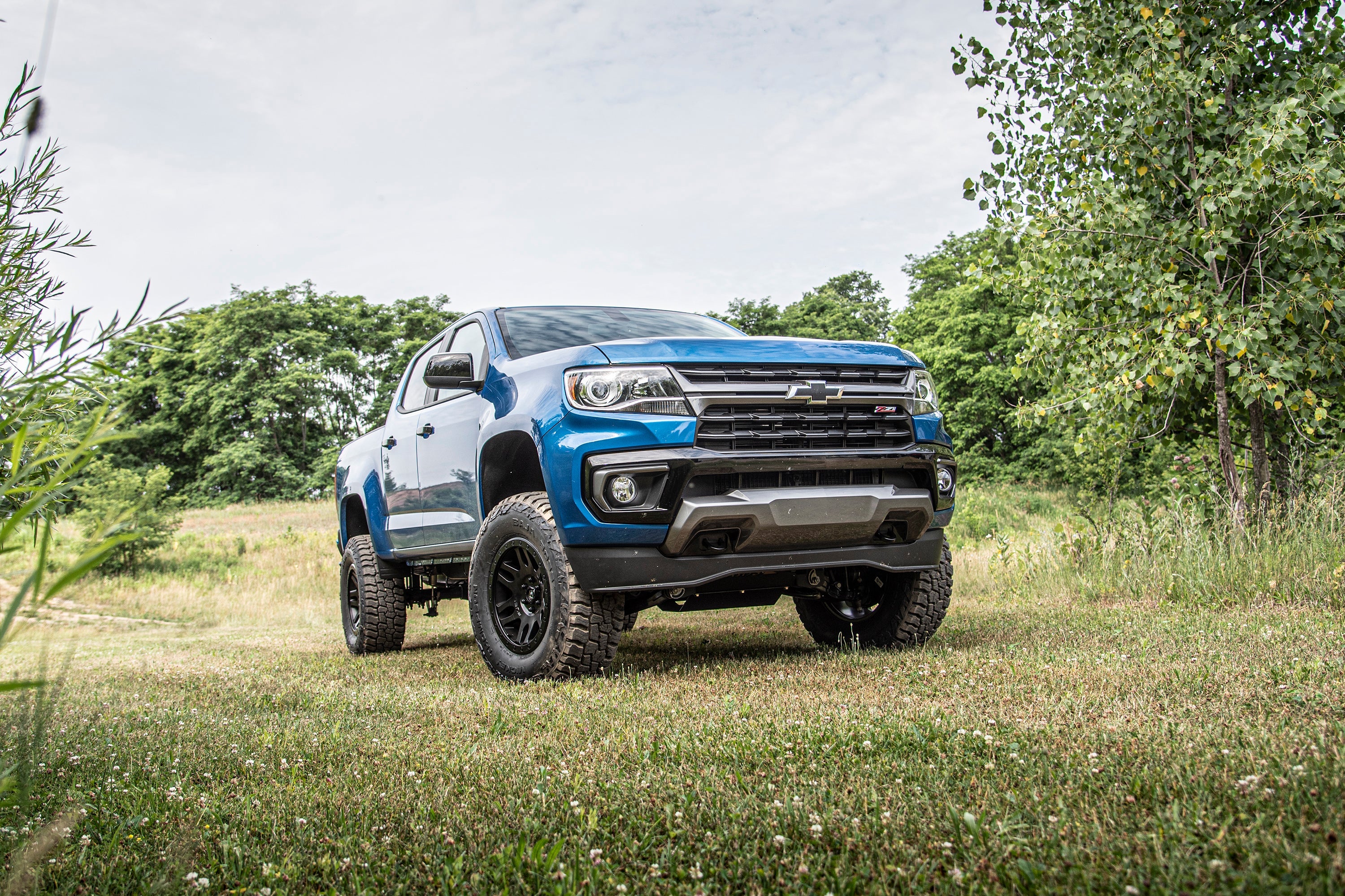 5.5 inch lift kit with FOX 2.5 coil-over installed on a blue Chevy Colorado in a grassy outdoor setting.