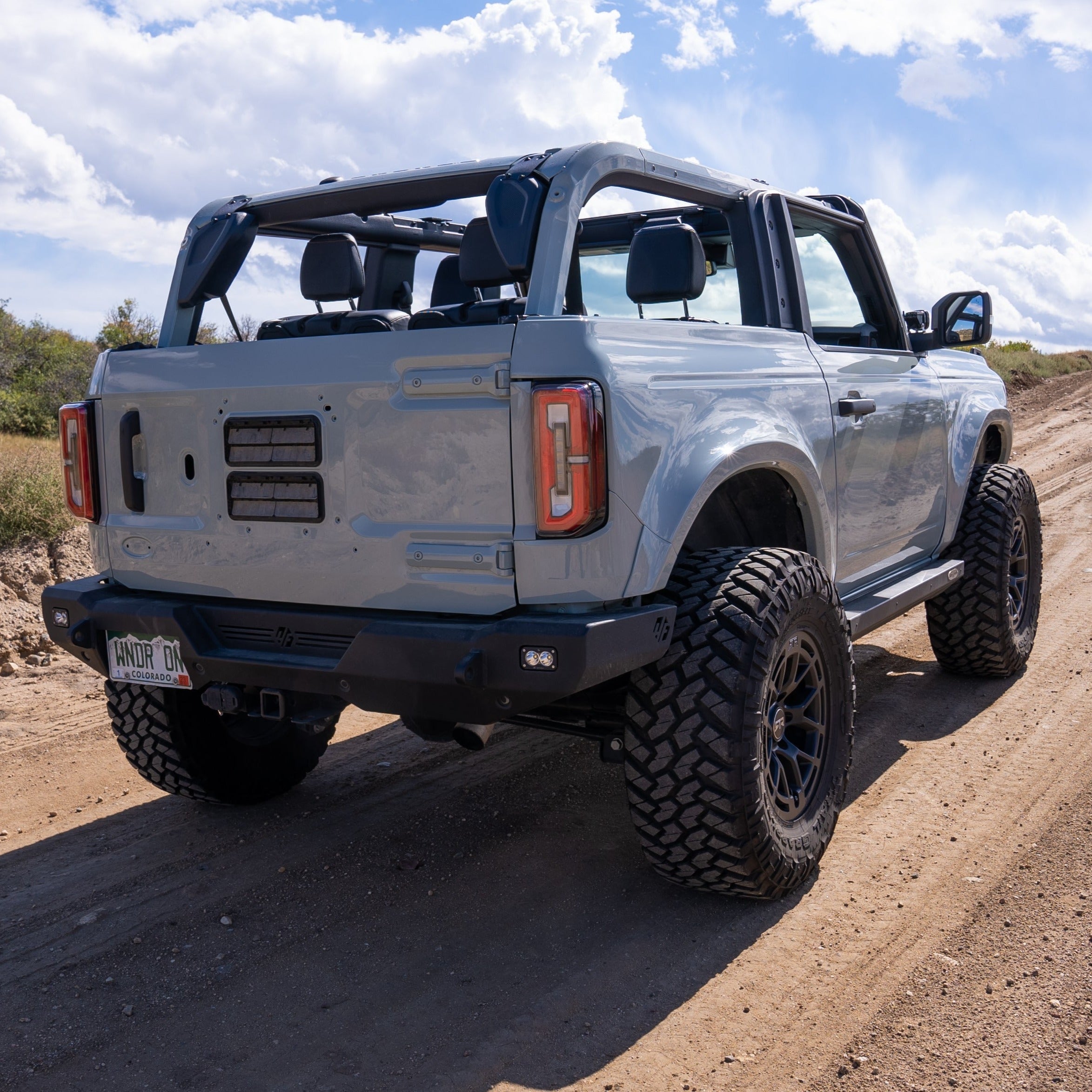 2021-2025 Ford Bronco 2-Door Rear Quarter Kit installed on a lifted Bronco on a dirt road, showcasing rugged offroad capability.
