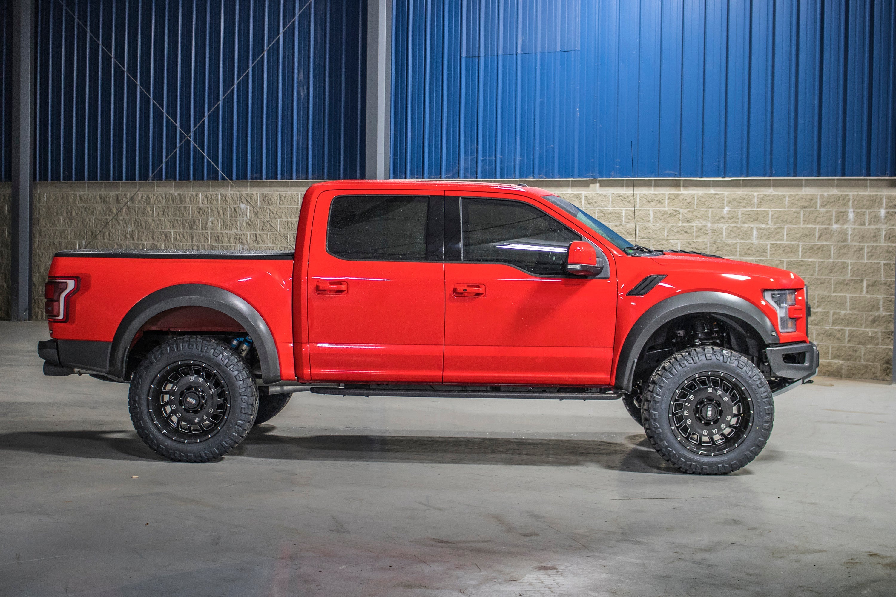 4-inch lift kit installed on a red Ford F150 Raptor, showcasing enhanced off-road capability and aggressive stance.