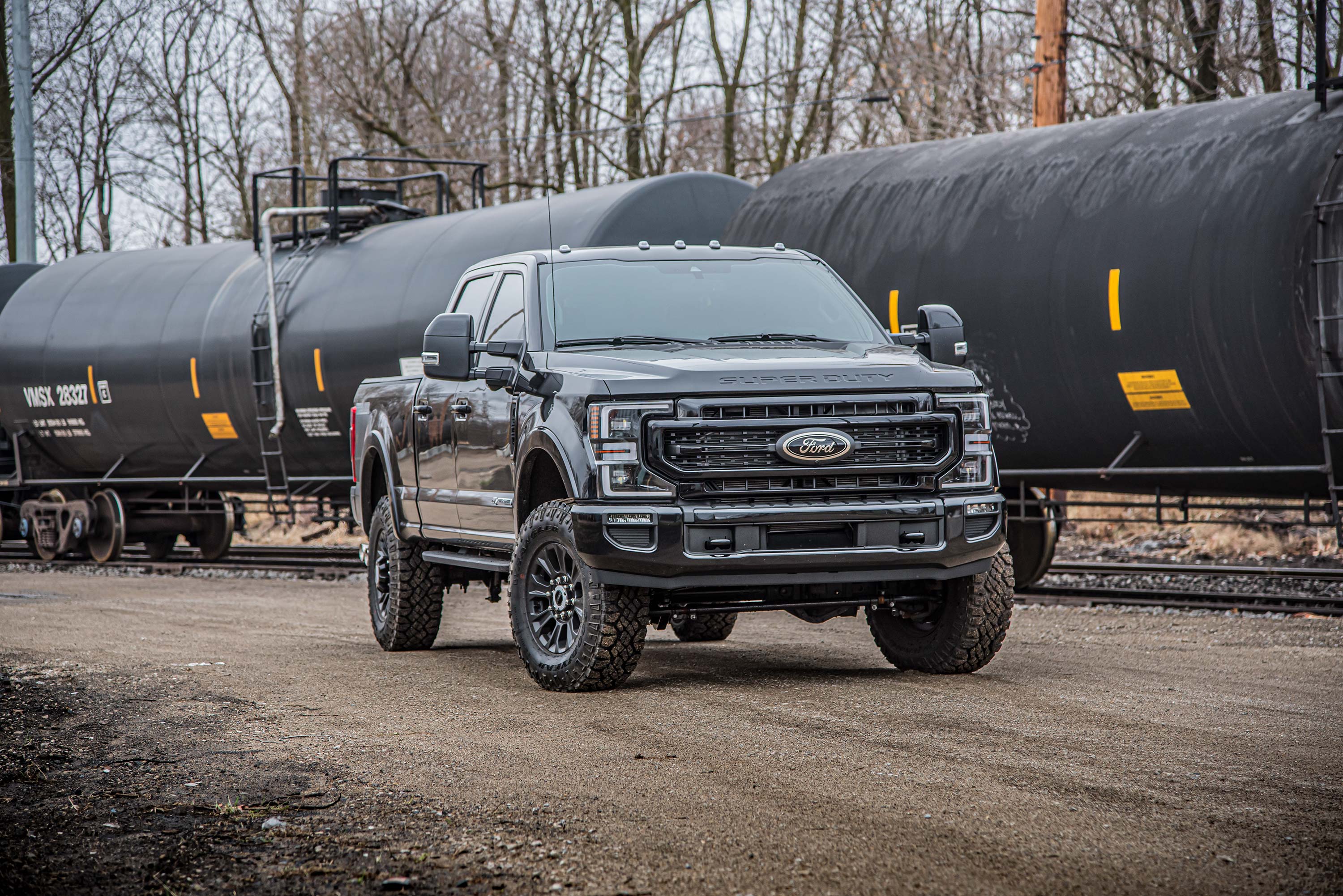 Ford F250/F350 Super Duty with a 1-2 inch leveling kit parked on a gravel road, showcasing its rugged design and enhanced lift.
