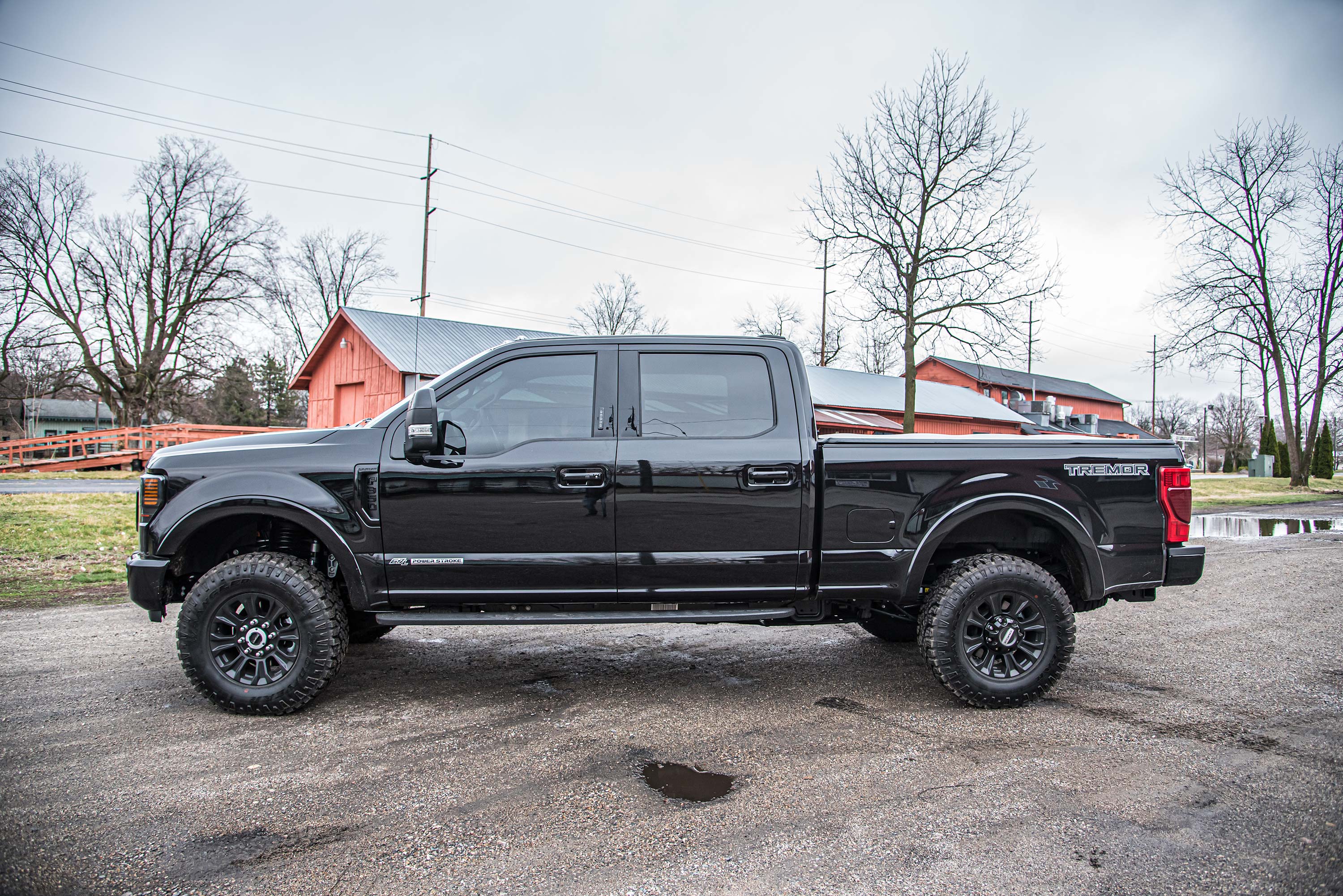 Black Ford F250 Super Duty with a leveling kit, showcasing a 2-inch lift, parked on a gravel surface.