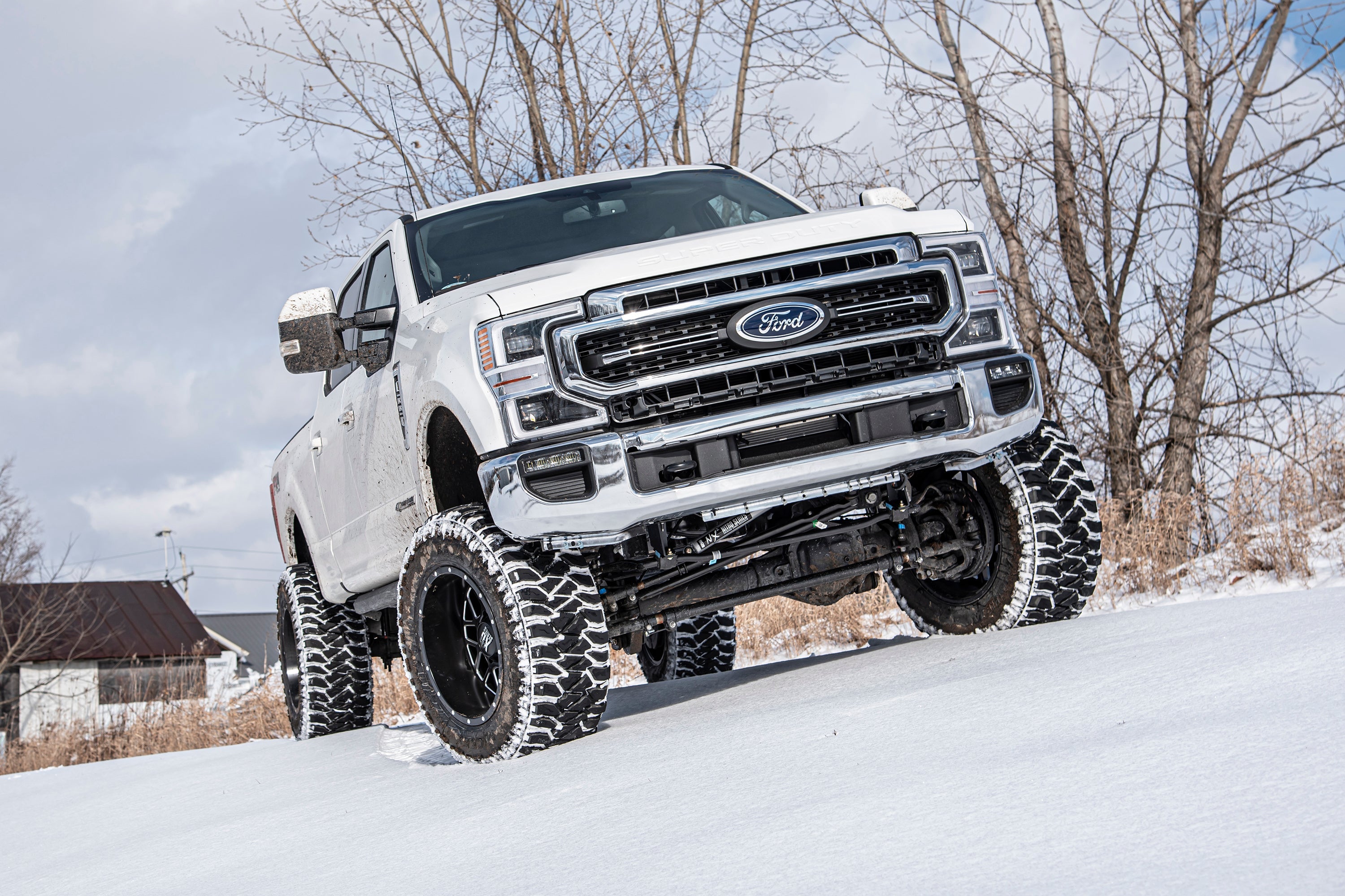 7-inch lift kit with 4-link and FOX 2.5 coil-over conversion installed on a Ford F250 Super Duty in snow.