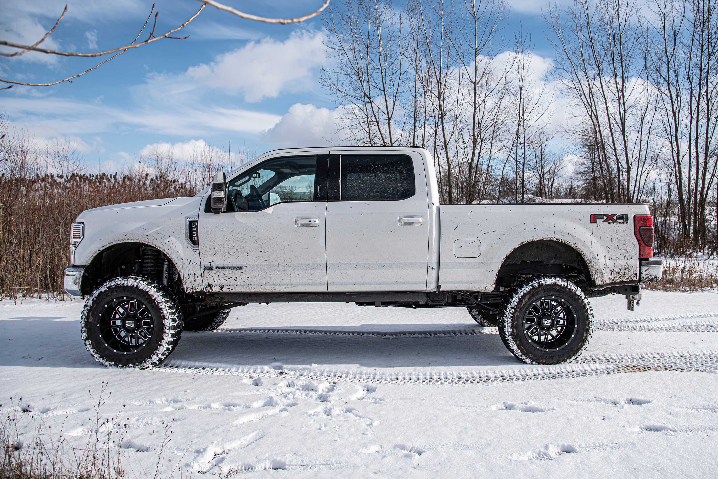 7-inch lift kit with 4-link and FOX 2.5 coil-over conversion installed on a Ford F250 Super Duty in snowy terrain.