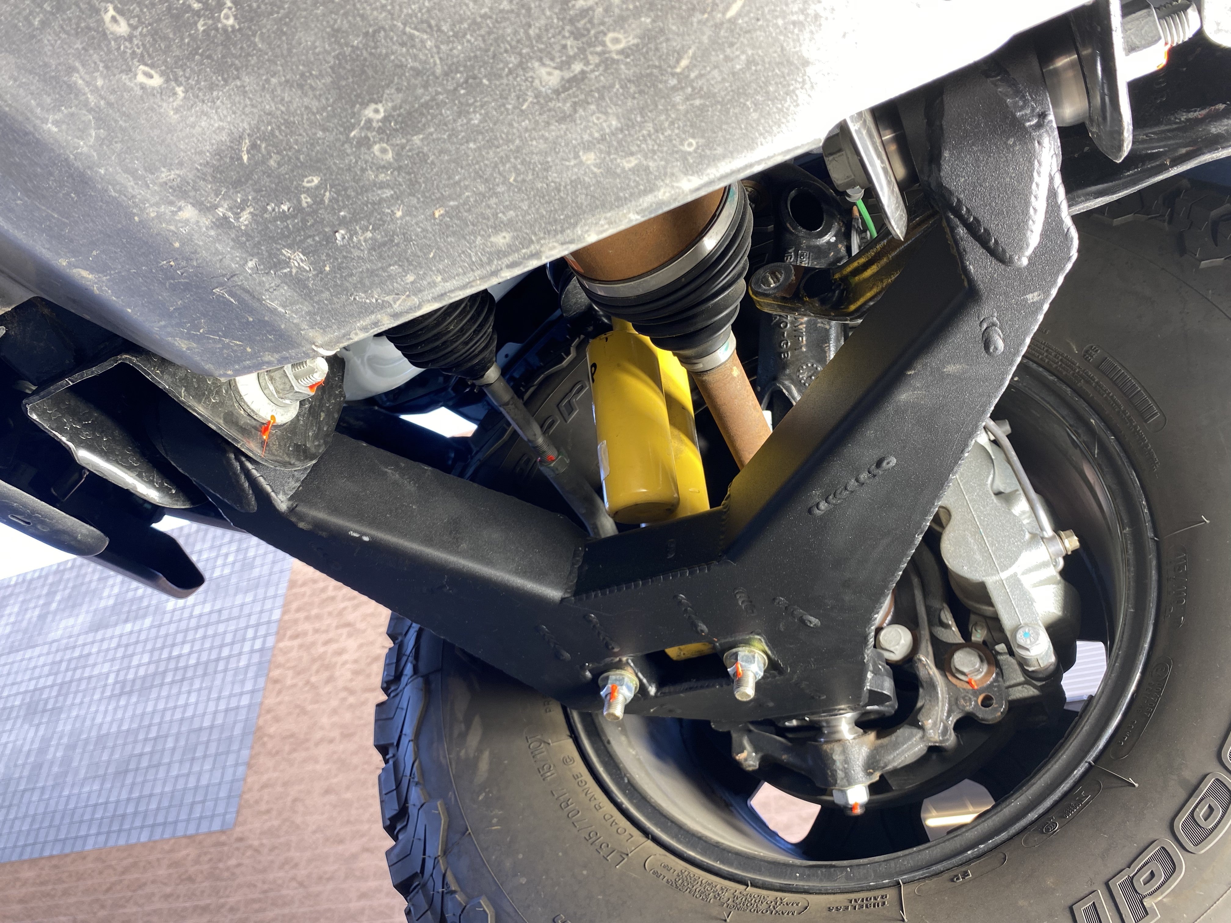 2021 and up Bronco fabricated lower arm kit with bypass shock mount, showcasing stock length installation under the vehicle.