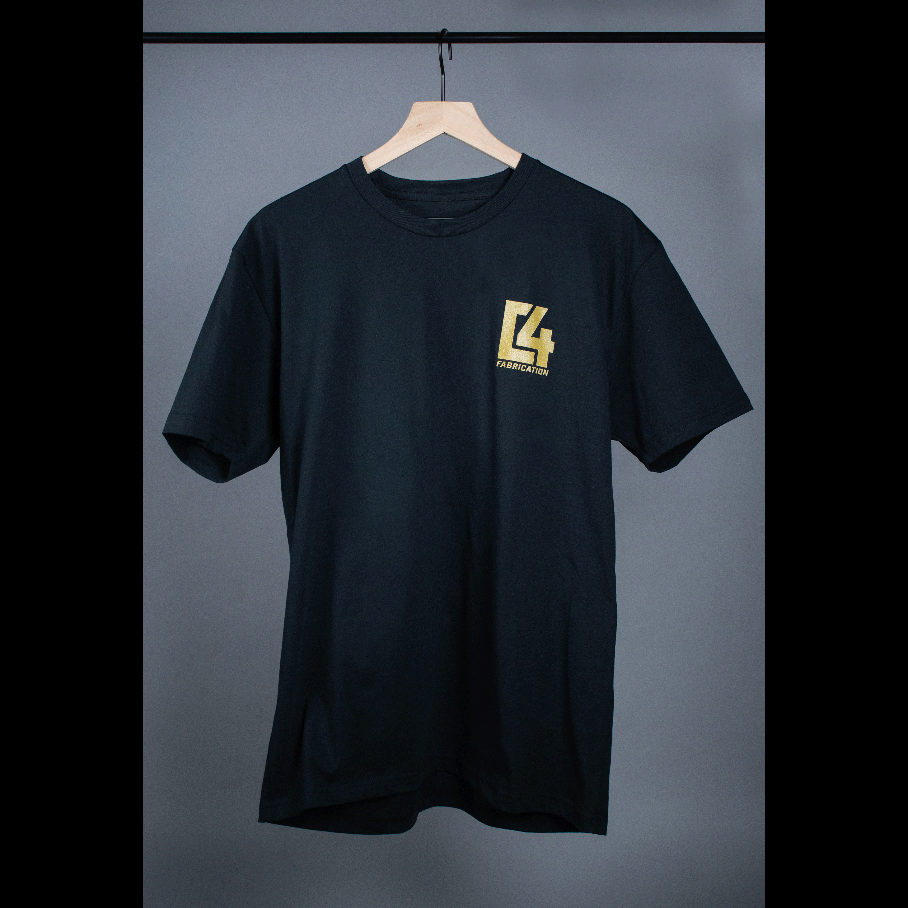 Black Badlands Tee featuring a yellow logo on the left chest, displayed on a hanger against a gray background.