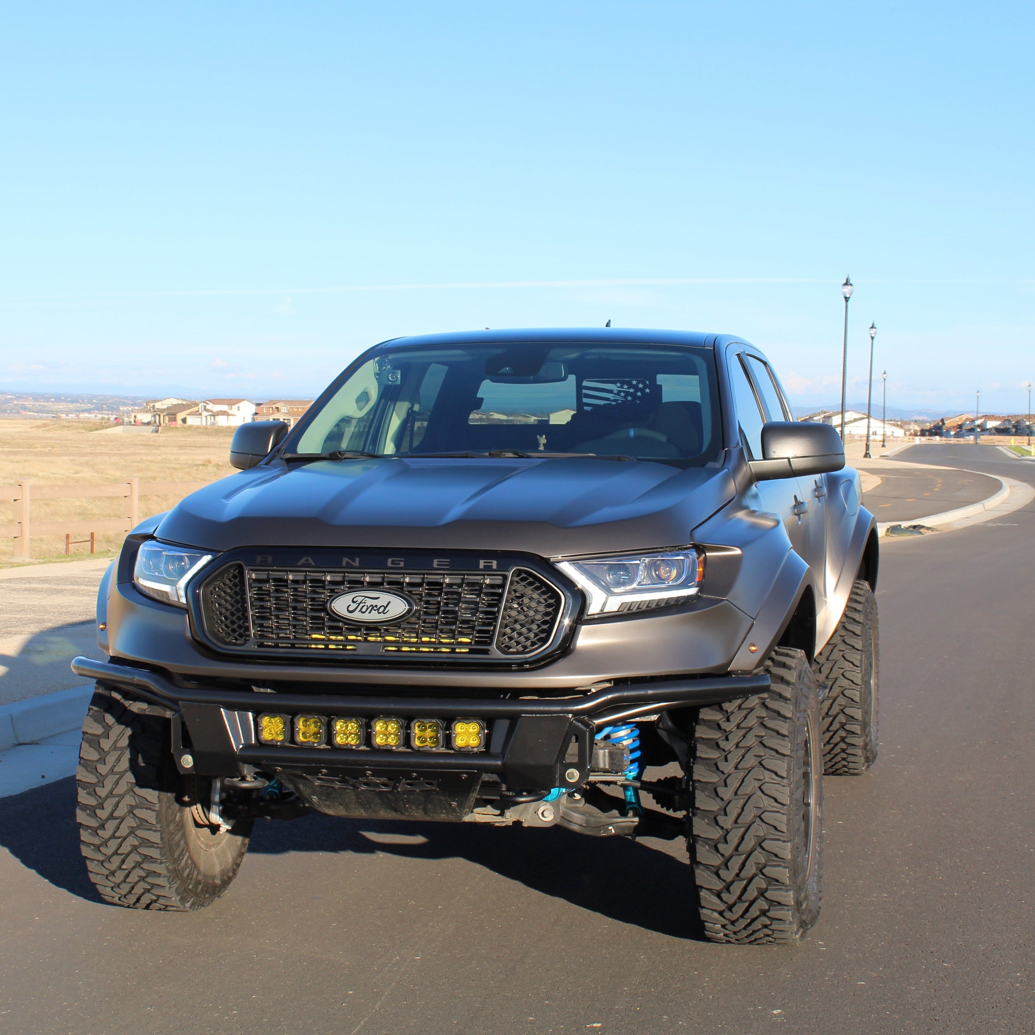 2019-2023 Ford Ranger with custom bedsides, showcasing an aggressive offroad stance and enhanced suspension on a paved road.