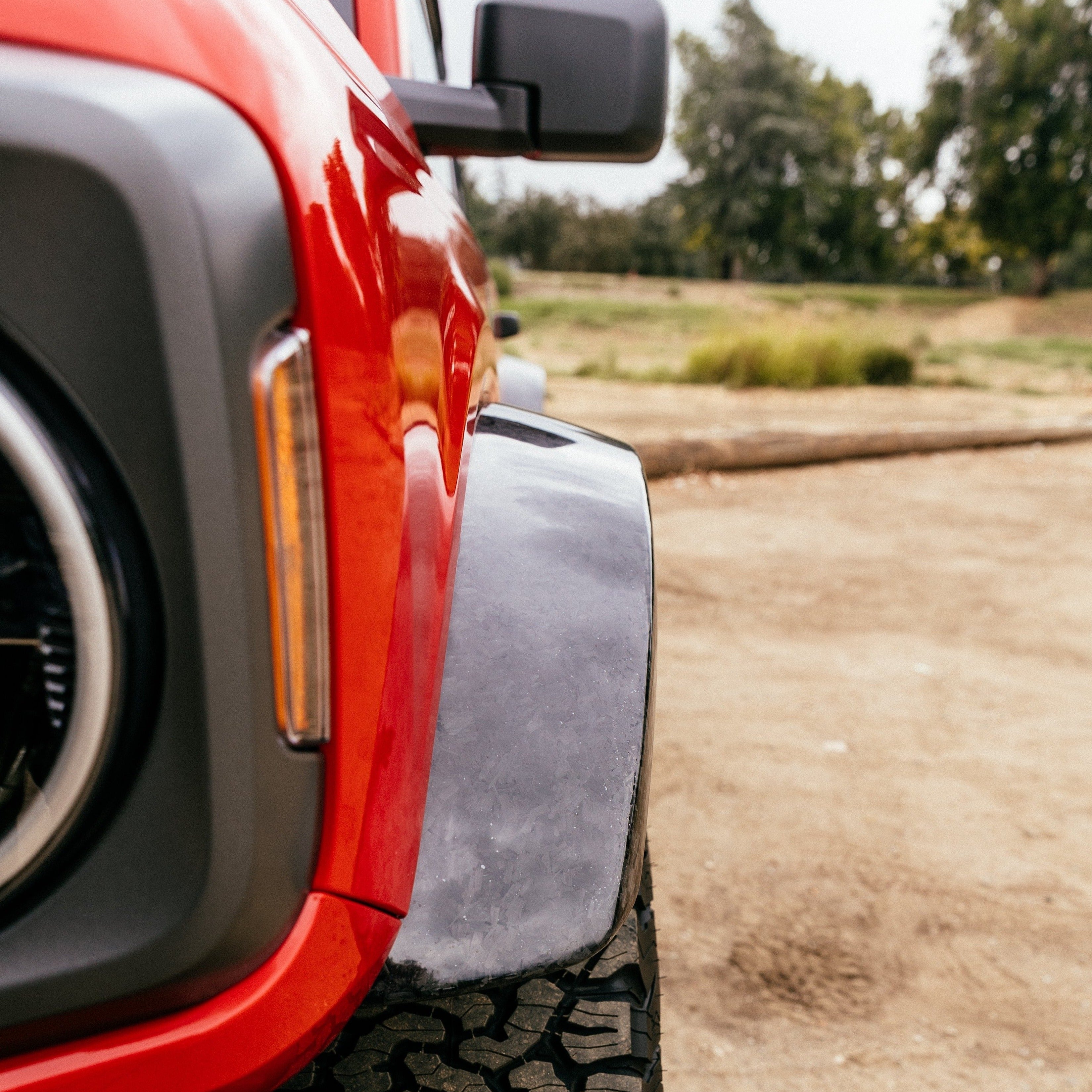 2021-2025 Ford Bronco Sasquatch Flares enhancing the rugged look and functionality of a red Bronco on rough terrain.