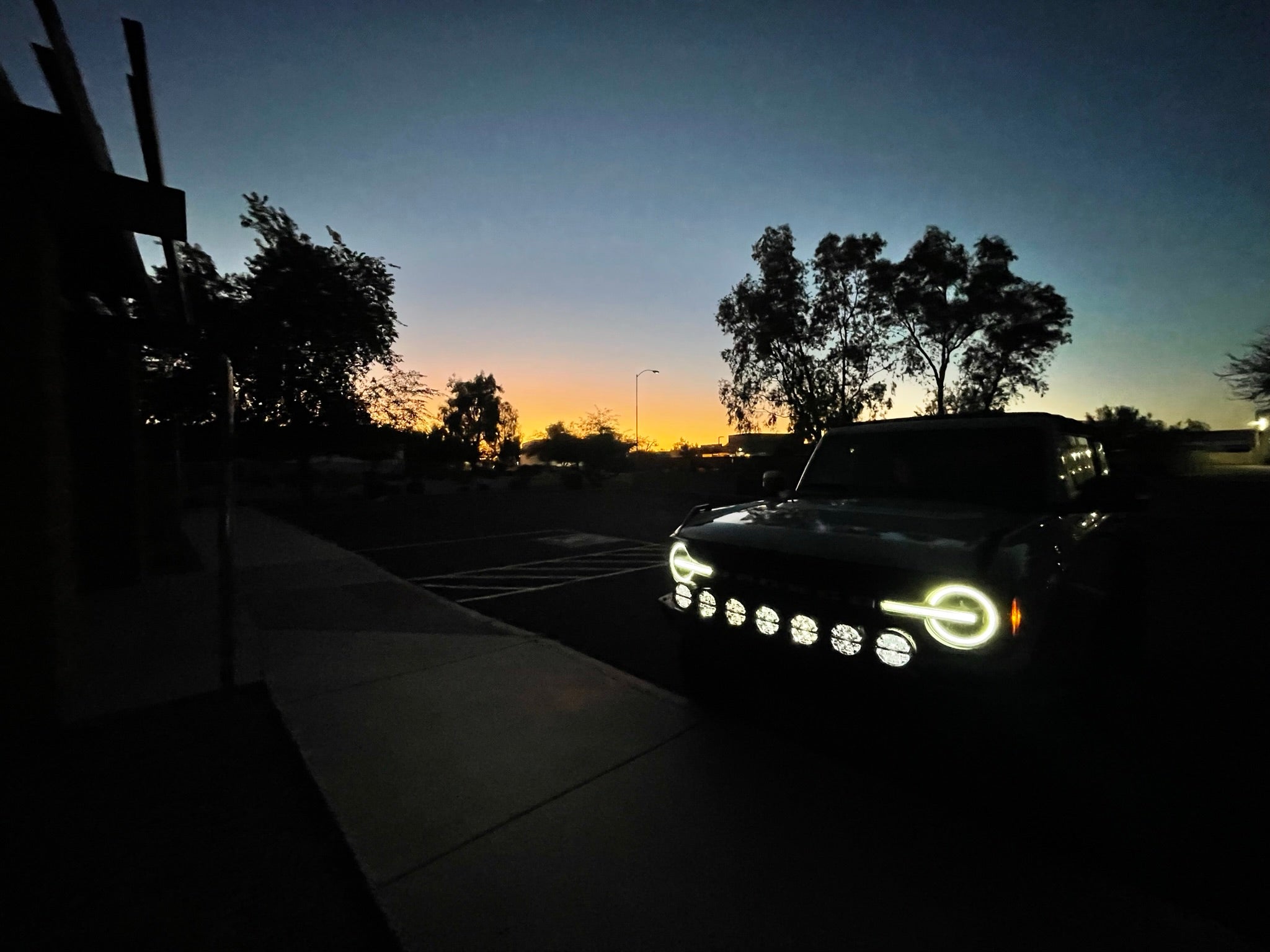 2022-UP Bronco Raptor Front Light Mount Kit showcasing a Bronco with custom lights at dusk, highlighting offroad capabilities.