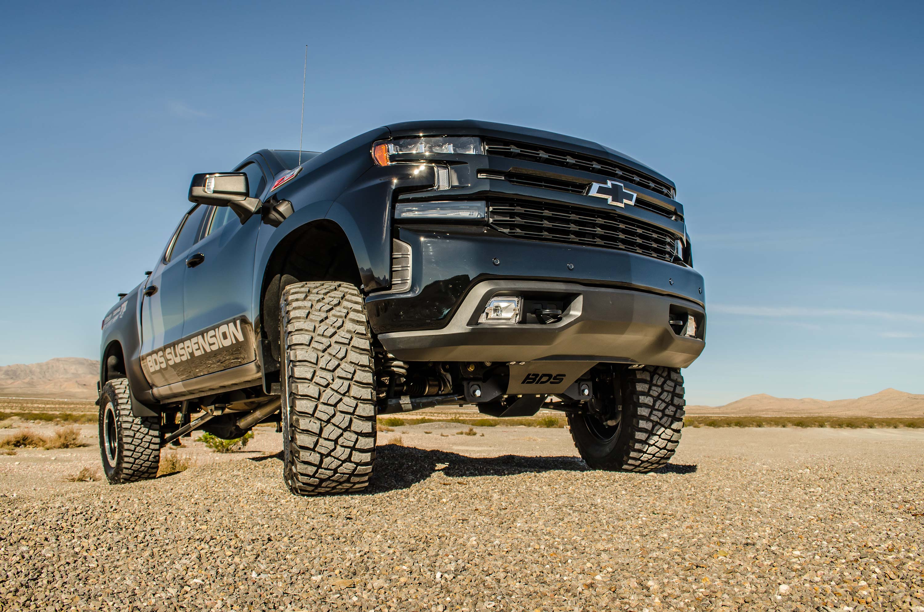 4-inch lift kit featuring FOX 2.5 Performance Elite Coil-Over on a lifted Chevy Trail Boss or GMC AT4 1500 in a desert setting.