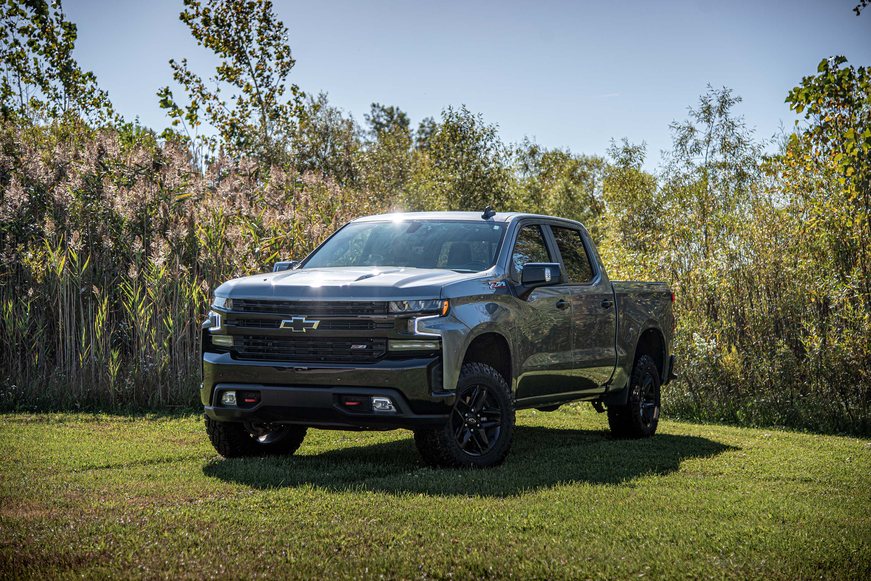 Chevy Silverado 1500 with a 2-inch leveling kit and FOX 2.0 struts, parked in a grassy area surrounded by trees.