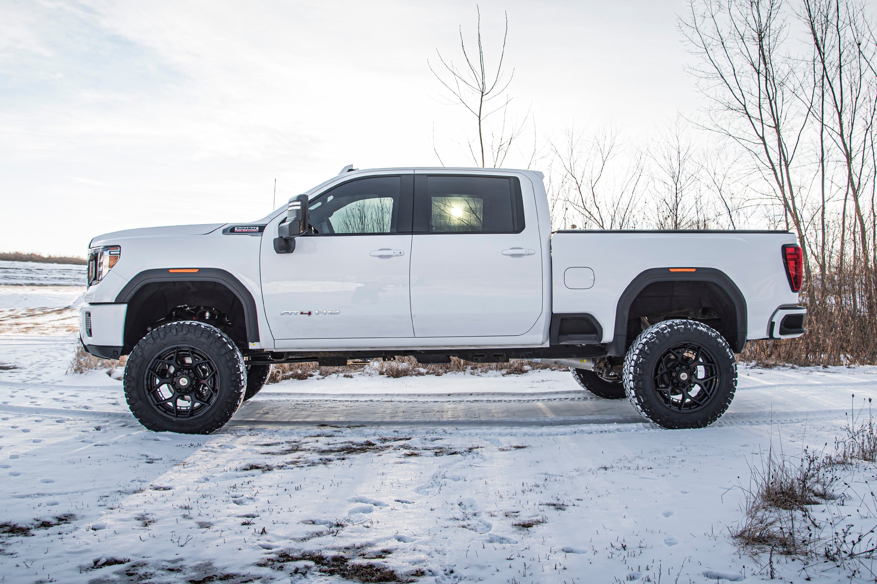 5-inch lift kit installed on a white Chevy Silverado 2500HD, showcasing enhanced off-road capability in a snowy landscape.