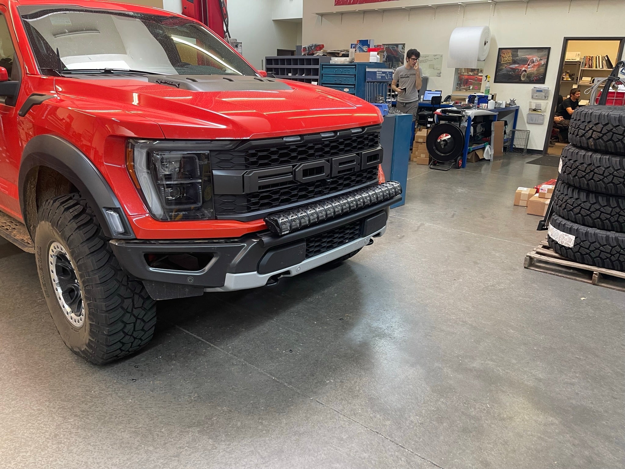 2024 Raptor Front Light Mount Kit displayed on a red Ford Raptor with modular bumper in a workshop setting.