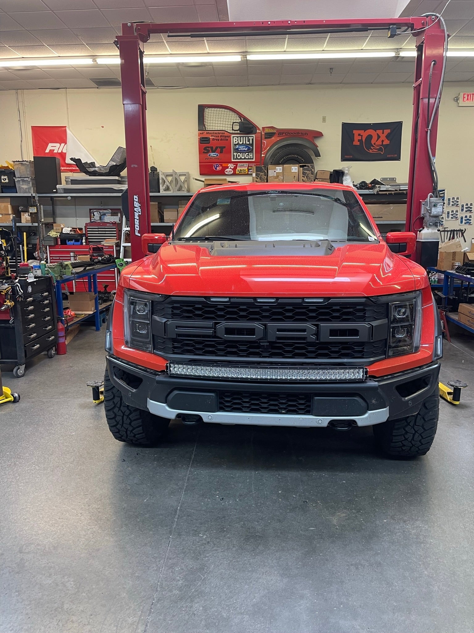 2024 Raptor Front Light Mount Kit displayed on a red Ford Raptor in a workshop, showcasing modular bumper compatibility.