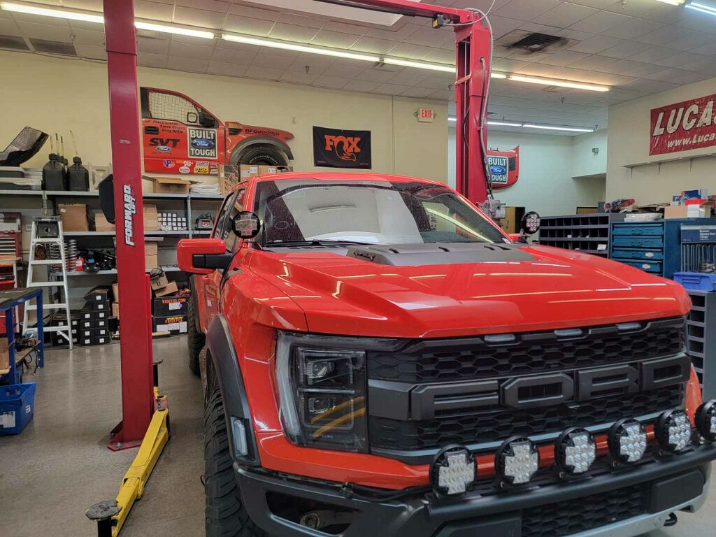 2024 Raptor Front Light Mount Kit displayed on a red Ford Raptor in a workshop, showcasing modular bumper compatibility.