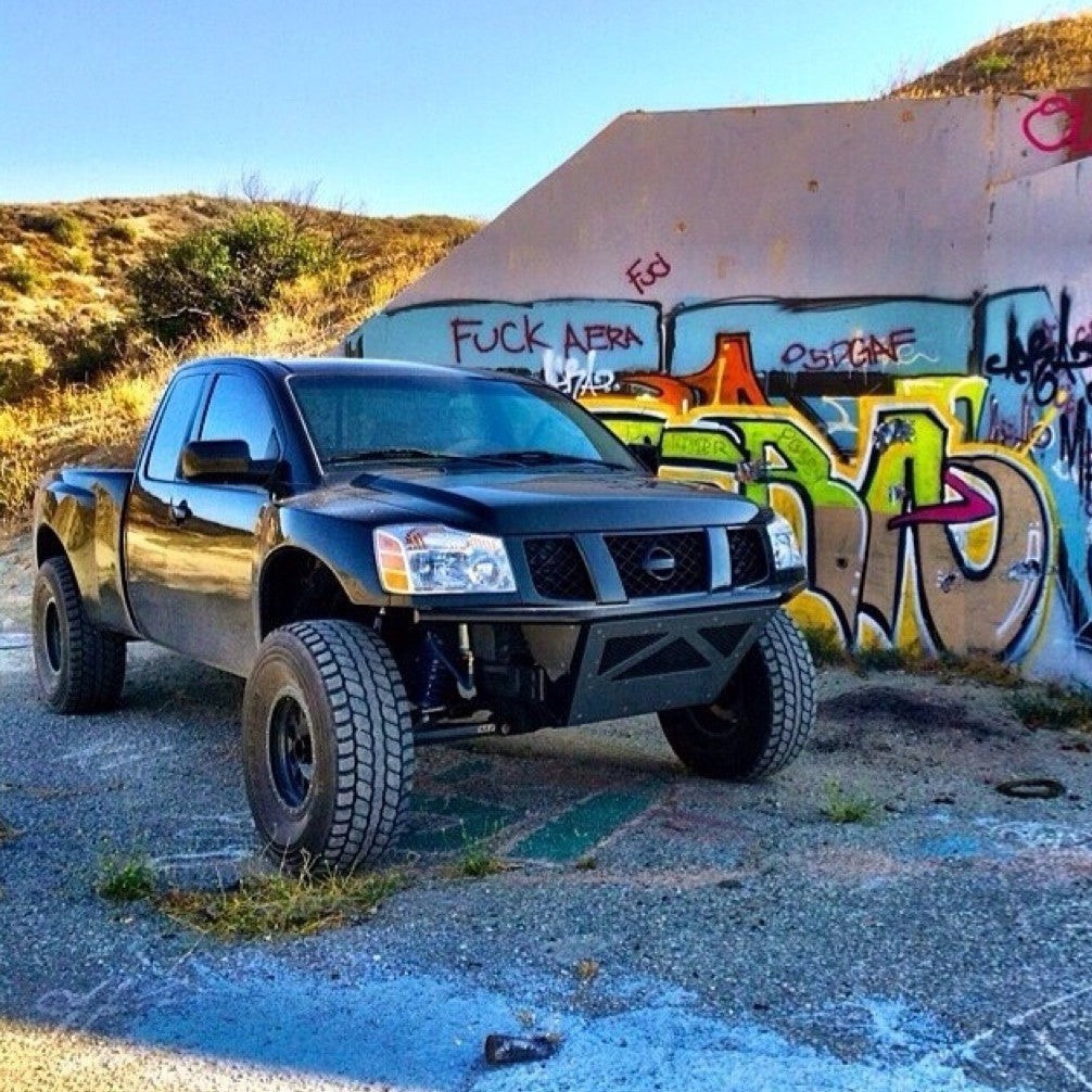 2004-2014 Nissan Titan fenders on a modified black truck parked near colorful graffiti, showcasing offroad capability.