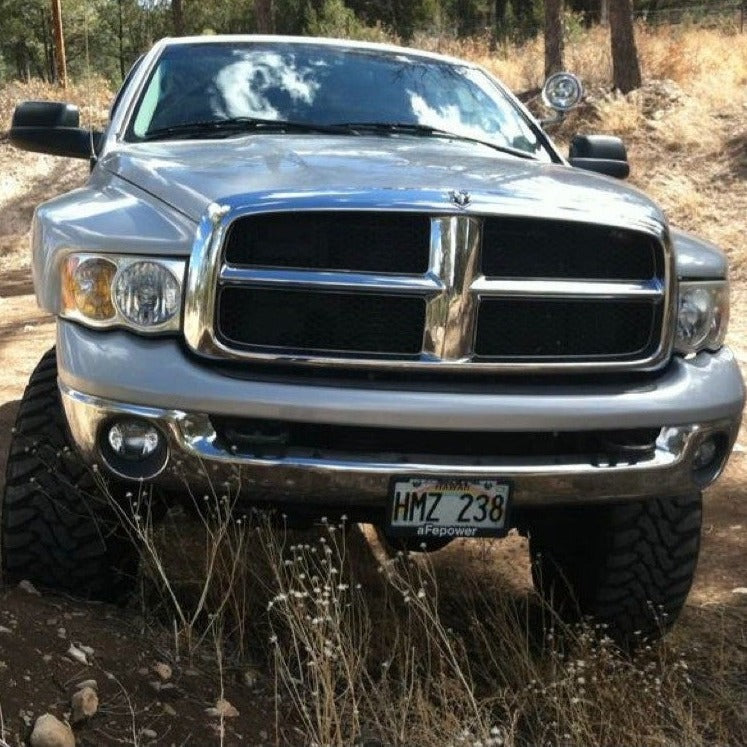 2003-2005 Dodge Ram fenders showcased on a lifted truck in a natural outdoor setting, highlighting rugged design.