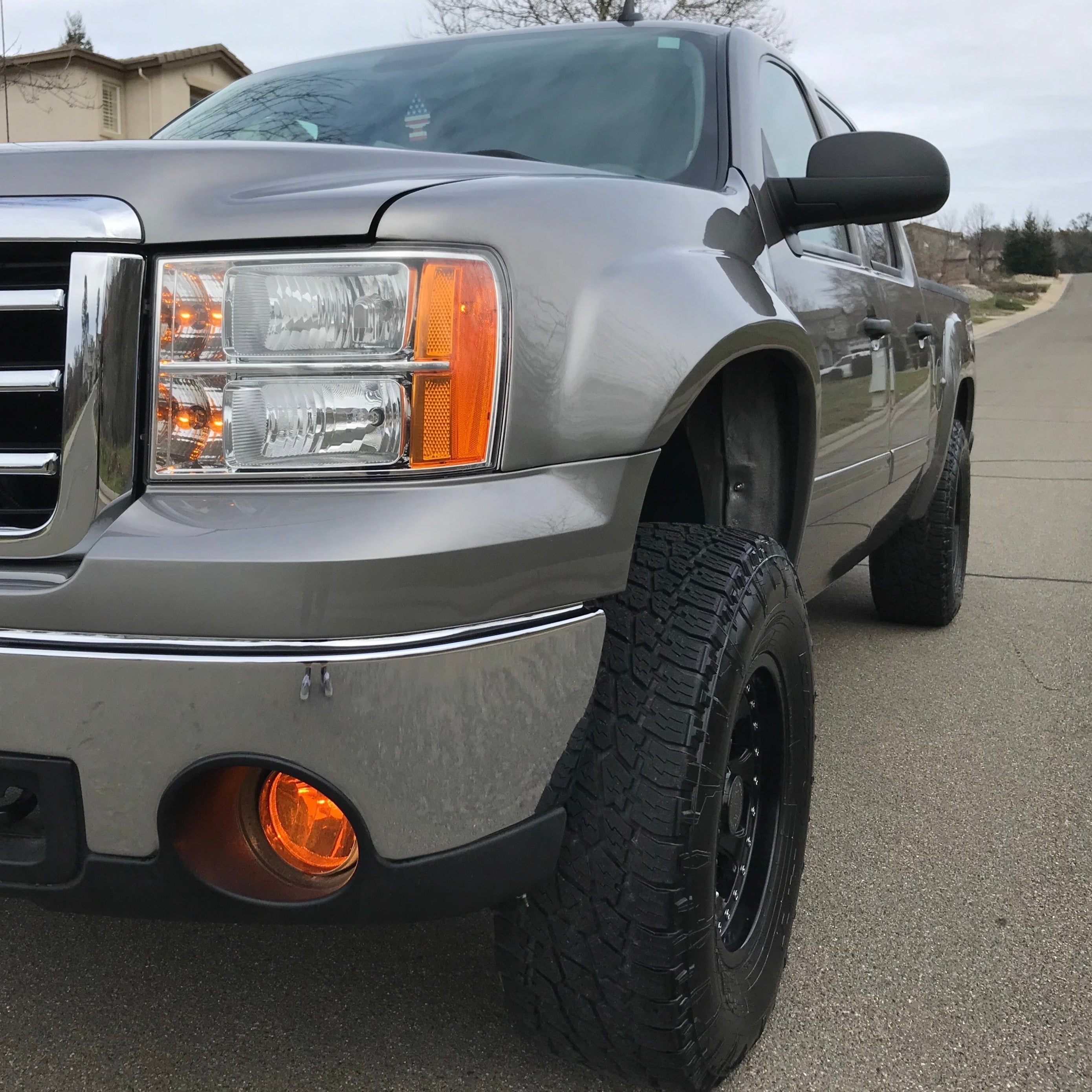 2007-2013 GMC Sierra with aftermarket fenders, showcasing a rugged design and enhanced tire clearance on a paved road.