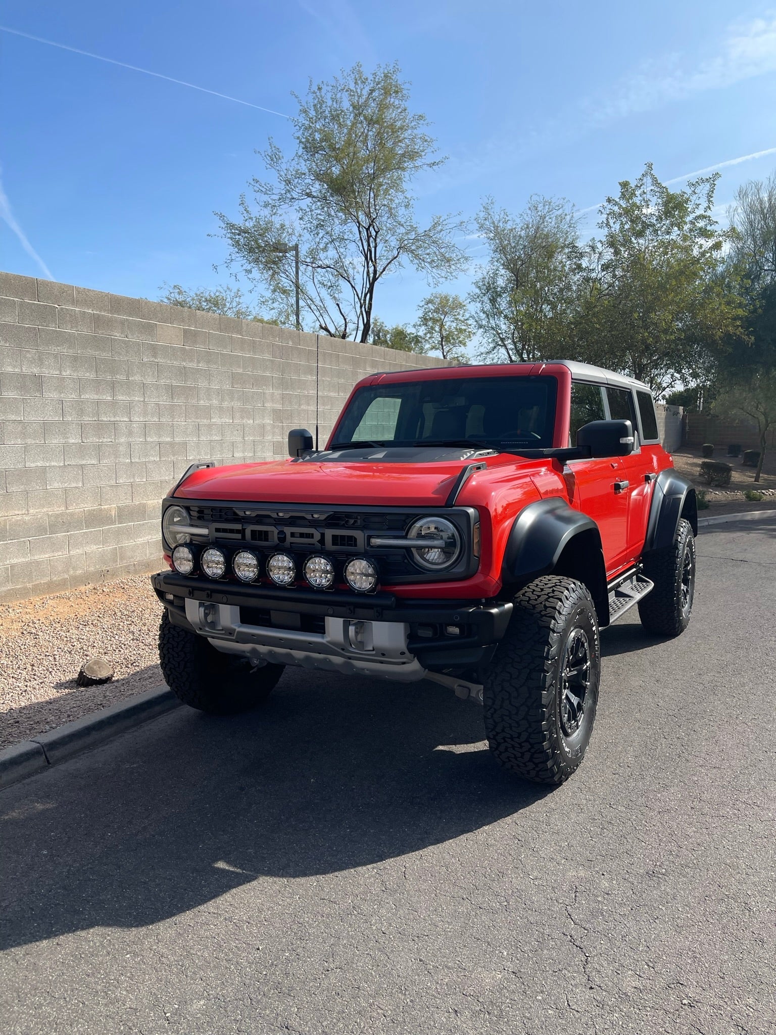 2022-UP Bronco Raptor with front light mount kit showcasing multiple lights, parked on a street with a desert backdrop.