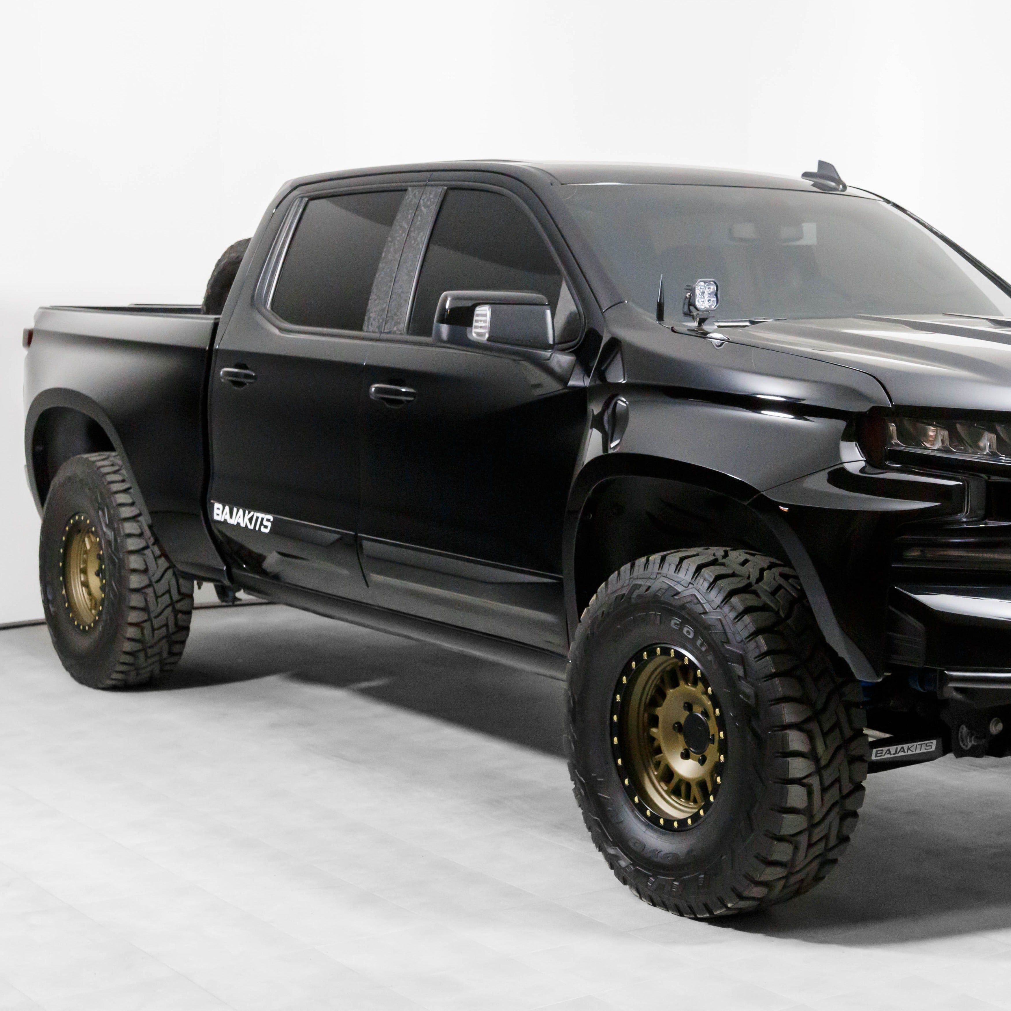 2019-2025 Chevrolet Silverado with custom bedsides, featuring rugged tires and a sleek black finish, showcasing offroad capability.