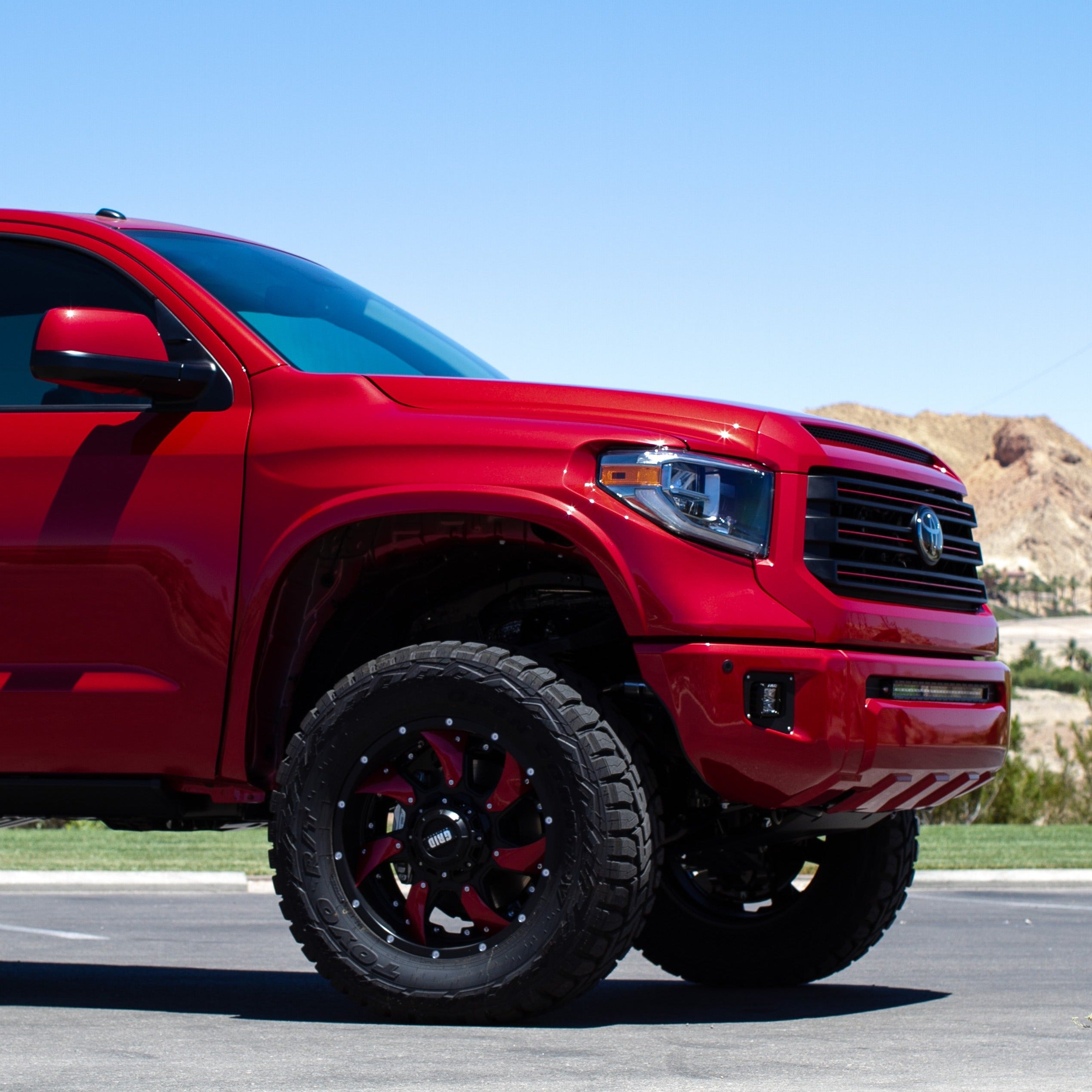 2014-2021 Toyota Tundra fenders showcasing a lifted red truck with oversized wheels and rugged tires.