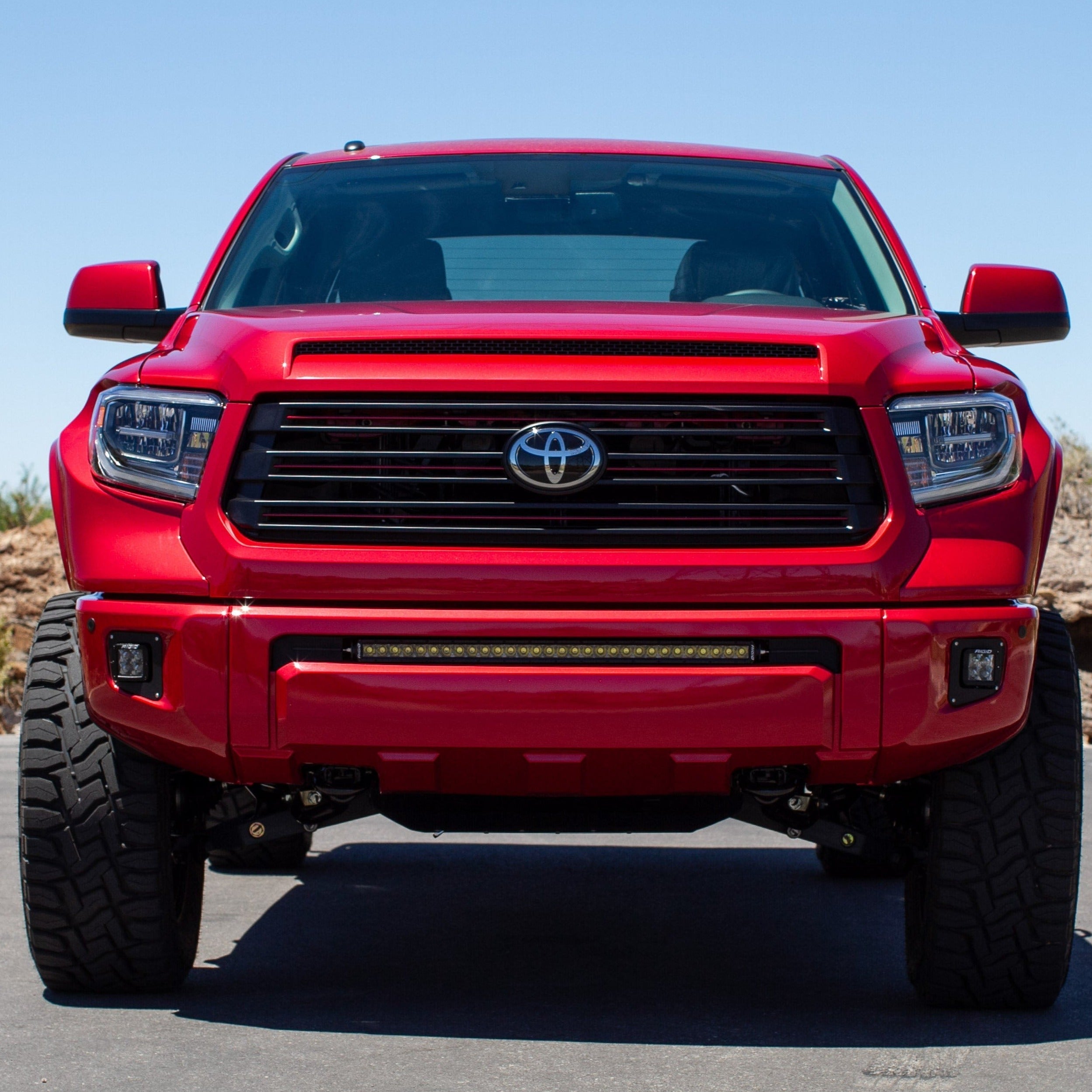 Front view of a red 2014-2021 Toyota Tundra showcasing aftermarket fenders and an aggressive stance.