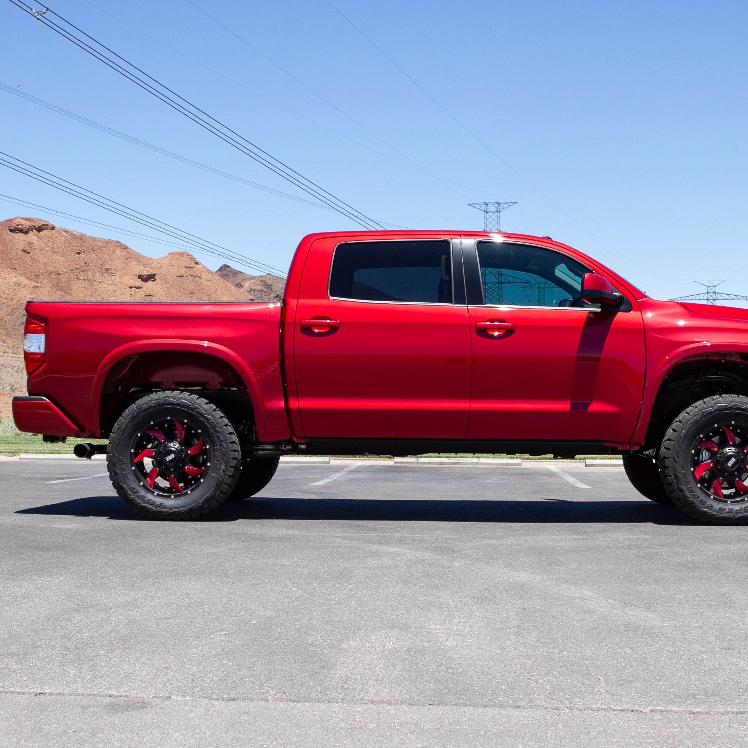 2014-2021 Toyota Tundra with custom red bedsides, showcasing an elevated off-road stance and rugged tires.