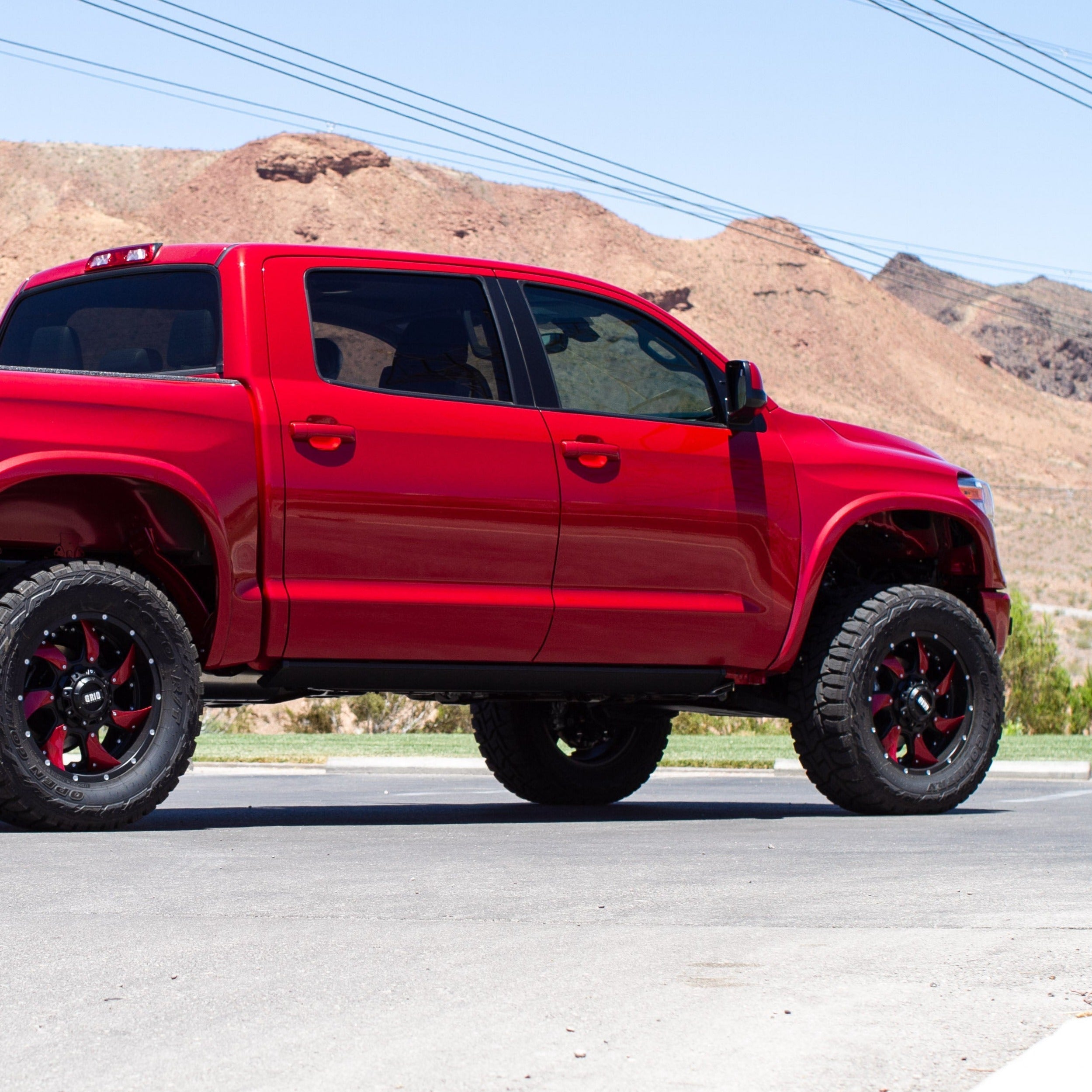 2014-2021 Toyota Tundra fenders showcased on a red truck with off-road tires in a desert landscape.