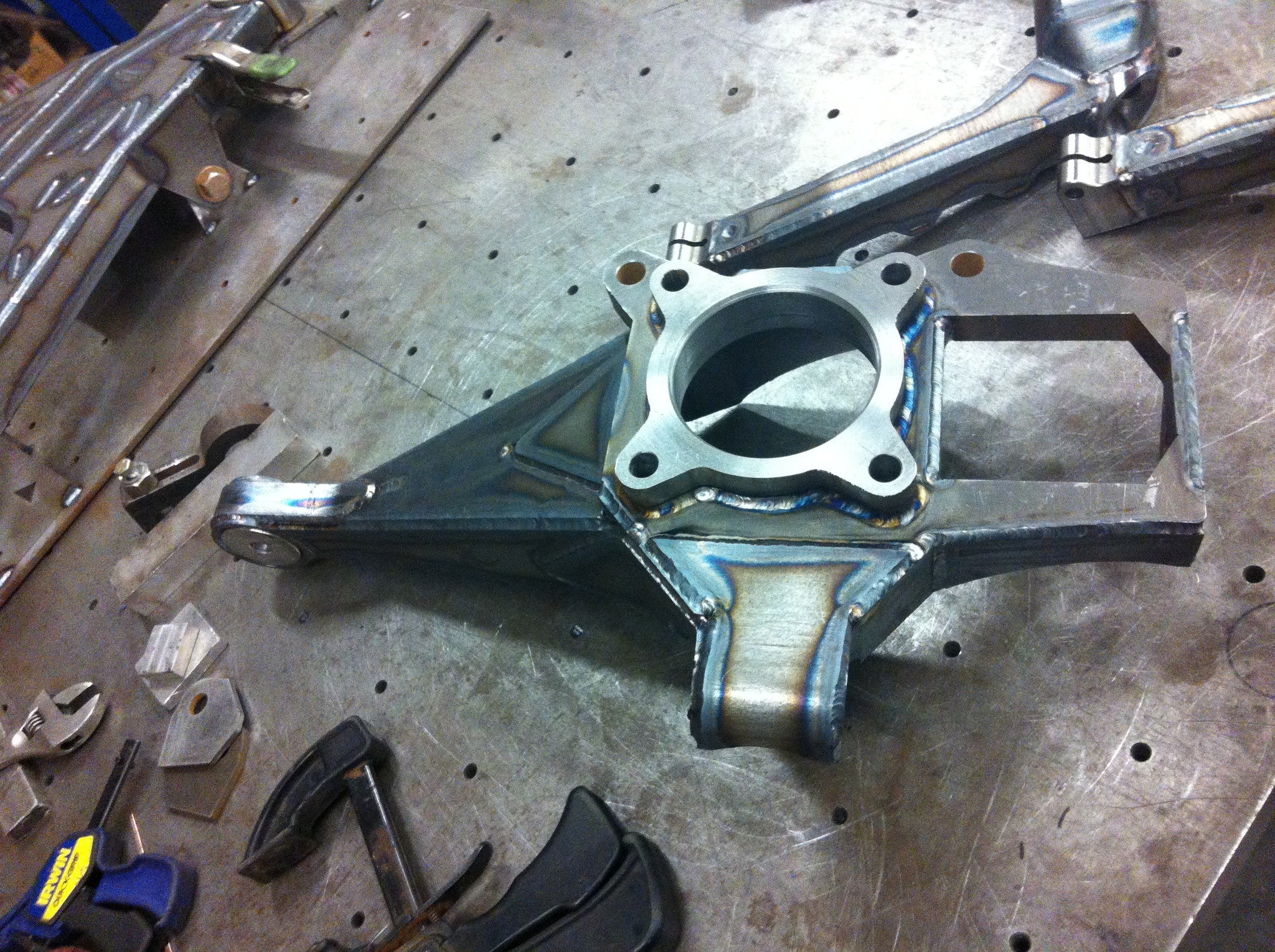 Long travel front suspension kit for 2010-2014 Raptor, showcasing a welded metal arm on a workbench.