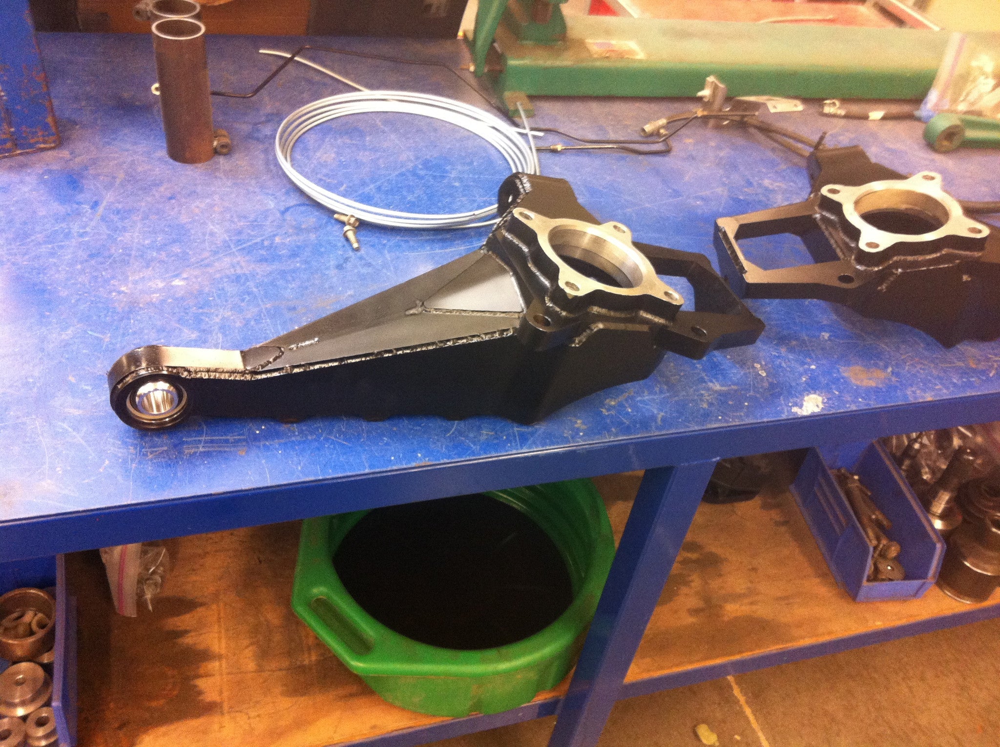 2010-2014 Raptor long travel front suspension kit components displayed on a workbench, showcasing durable metal parts.