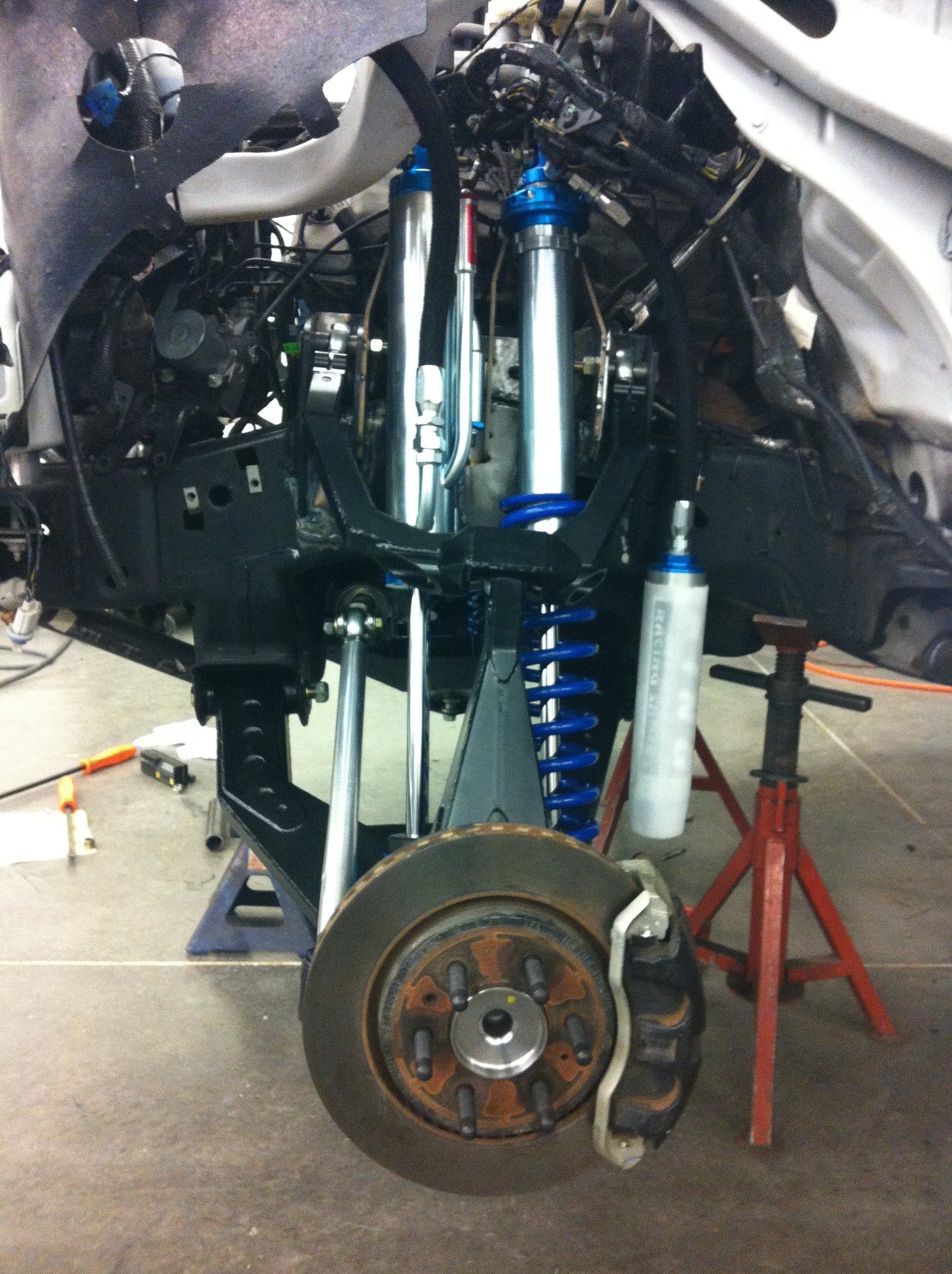 2010-2014 Raptor long travel front suspension kit showcasing shock absorbers, control arms, and brake components.