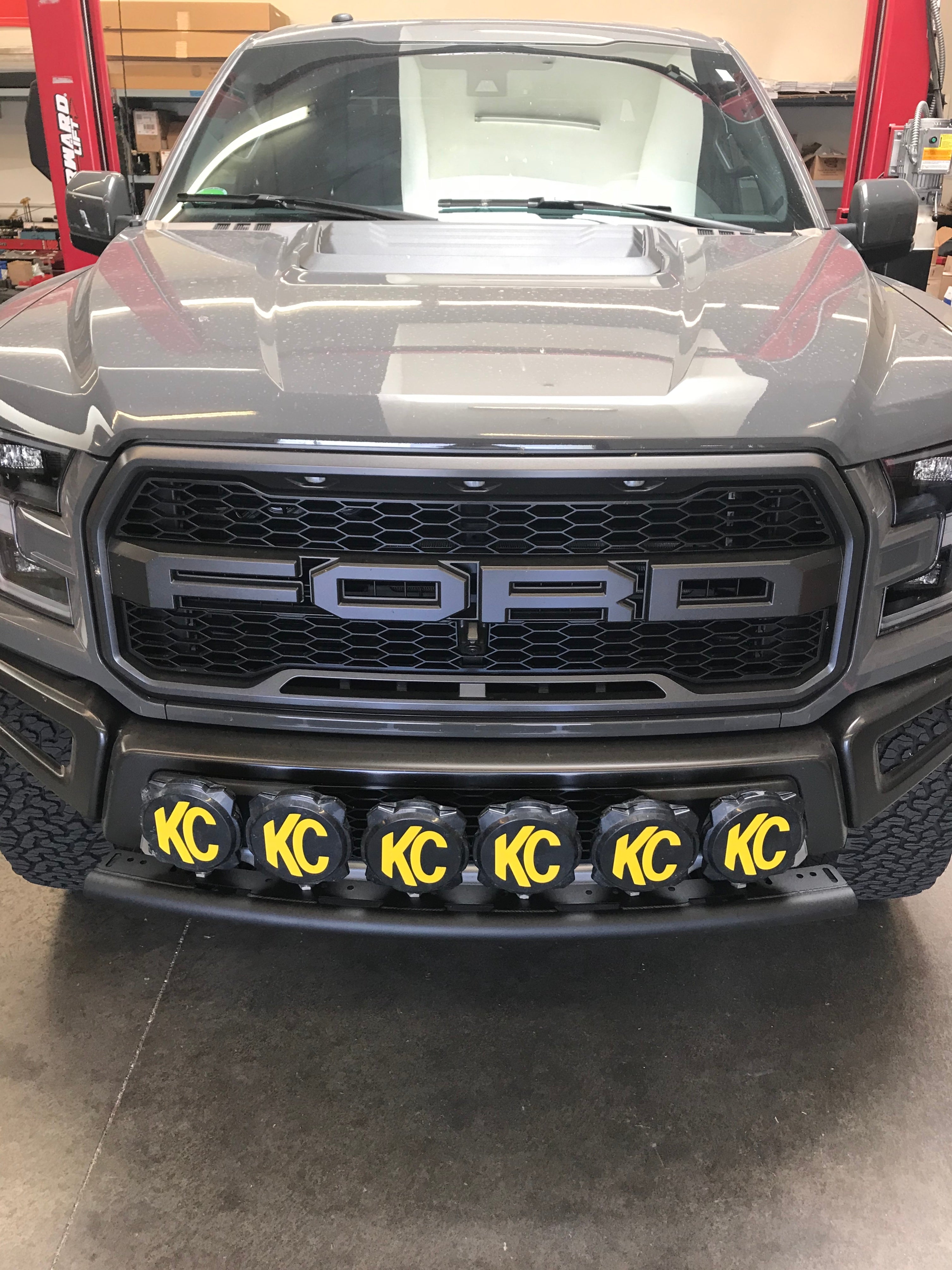 Single tube light mount for 2015+ F150 and 2017+ Raptor, featuring KC lights on a stock bumper. Ideal for offroad use.