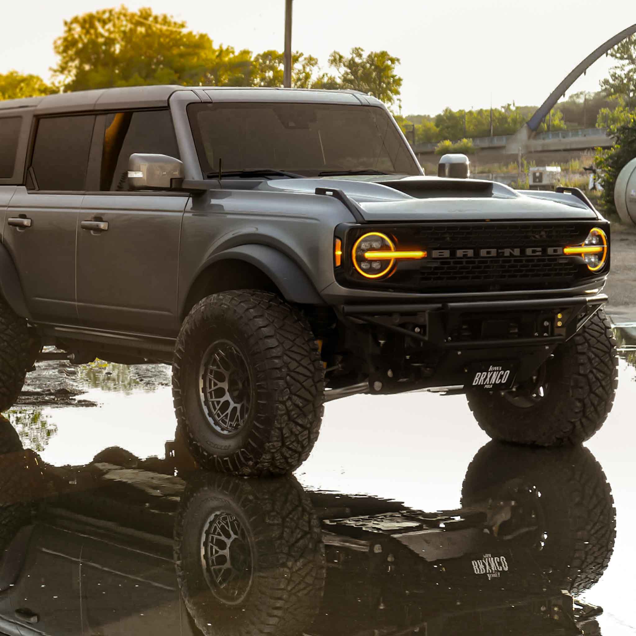 2021-2025 Ford Bronco Ram Air Hood on a modified Bronco with aggressive styling and off-road tires, reflecting in water.