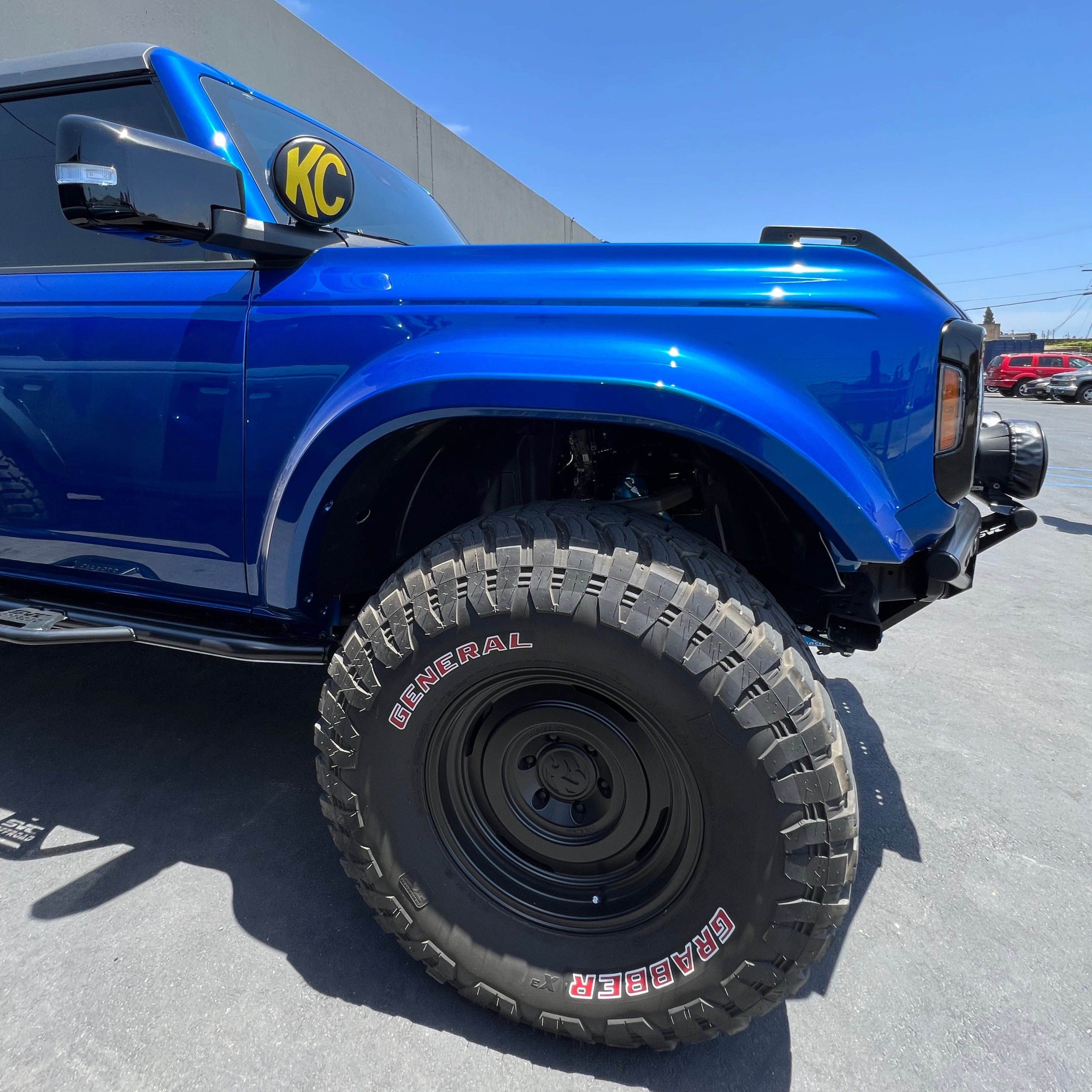 2021-2025 Ford Bronco fenders showcasing a blue truck with rugged tires, emphasizing off-road capability and style.