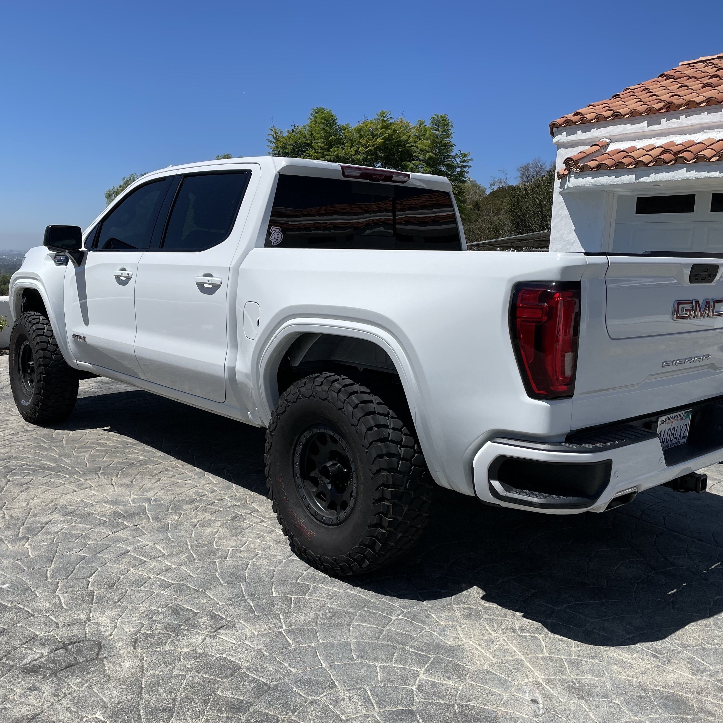 2019-2025 GMC Sierra with aftermarket bedsides, showcasing a lifted stance and rugged tires against a clear sky.