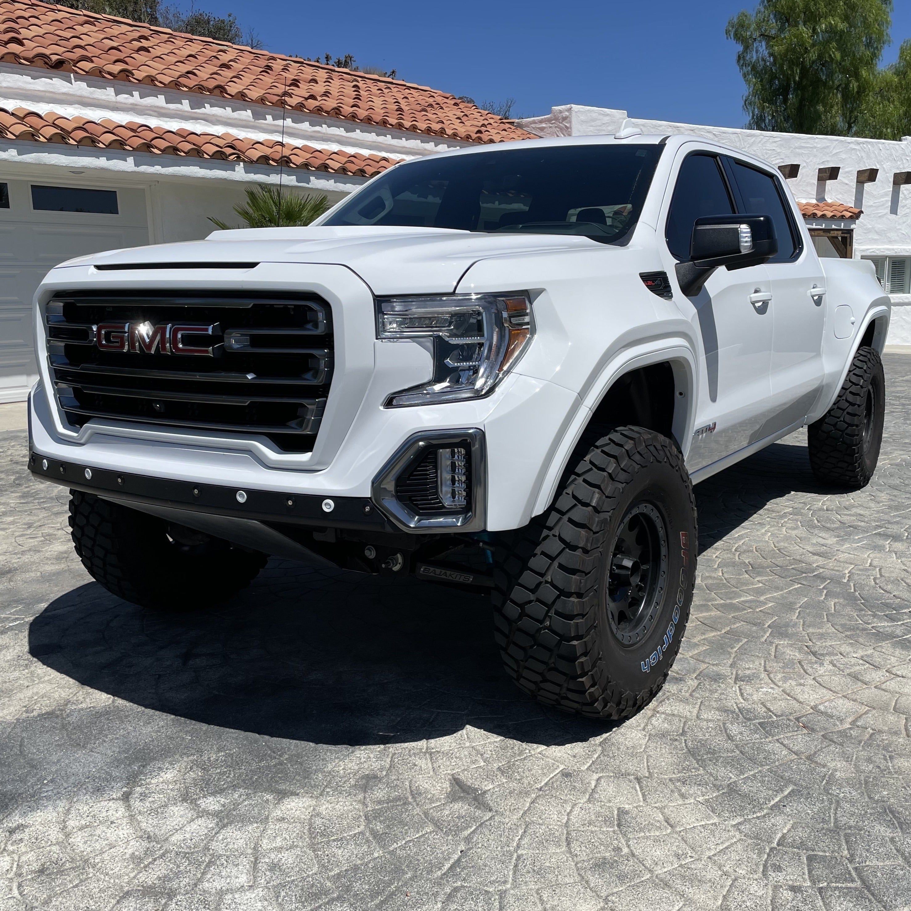 2019-2025 GMC Sierra fenders displayed on a lifted white truck with aggressive tires, showcasing offroad capabilities.