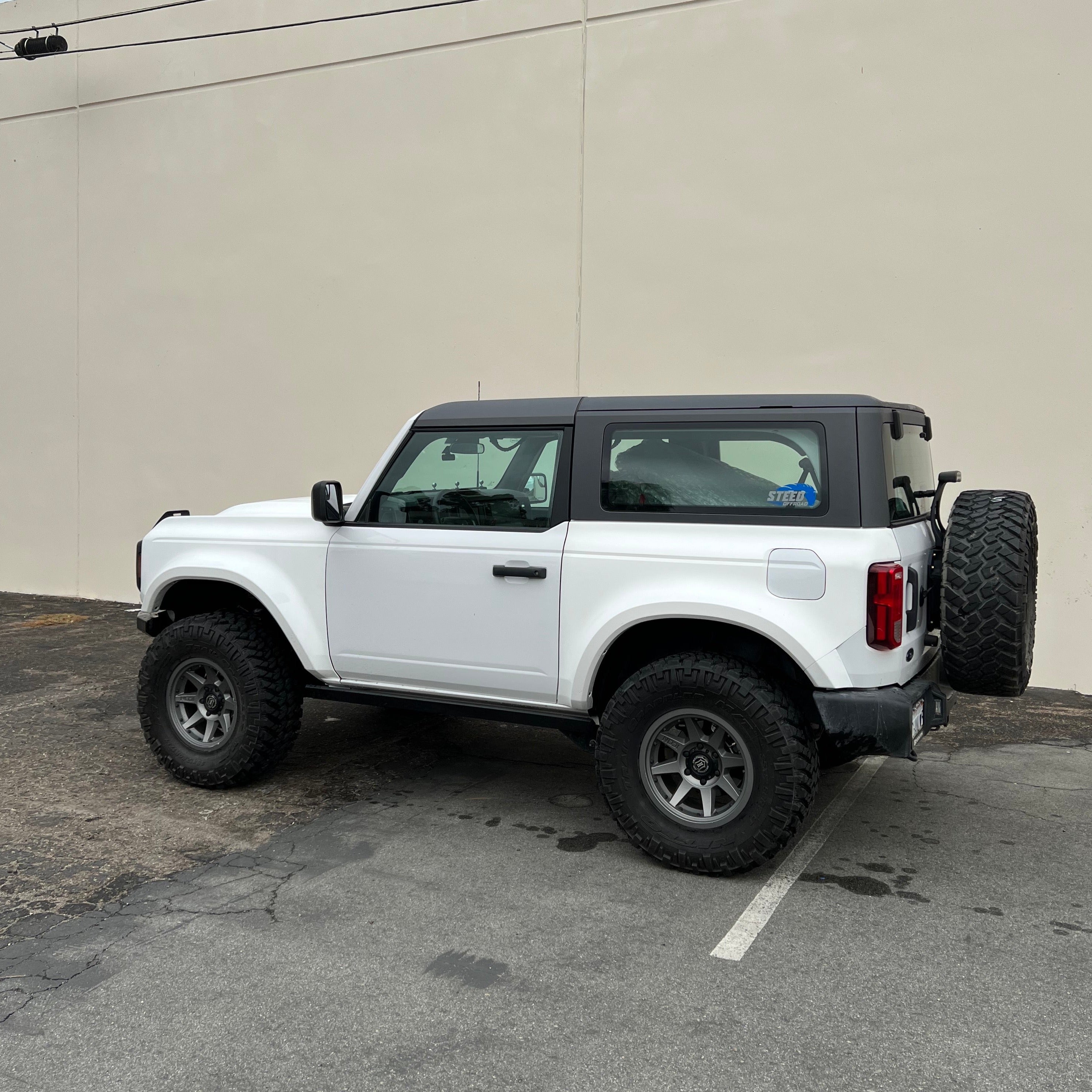2021-2025 Ford Bronco 2-Door with rear quarter kit, showcasing rugged design and off-road capabilities in a parking lot.
