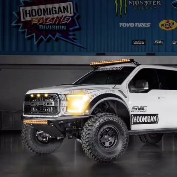 2017-2020 Ford Raptor fenders showcased on a modified truck with offroad tires and LED light bar in a garage setting.